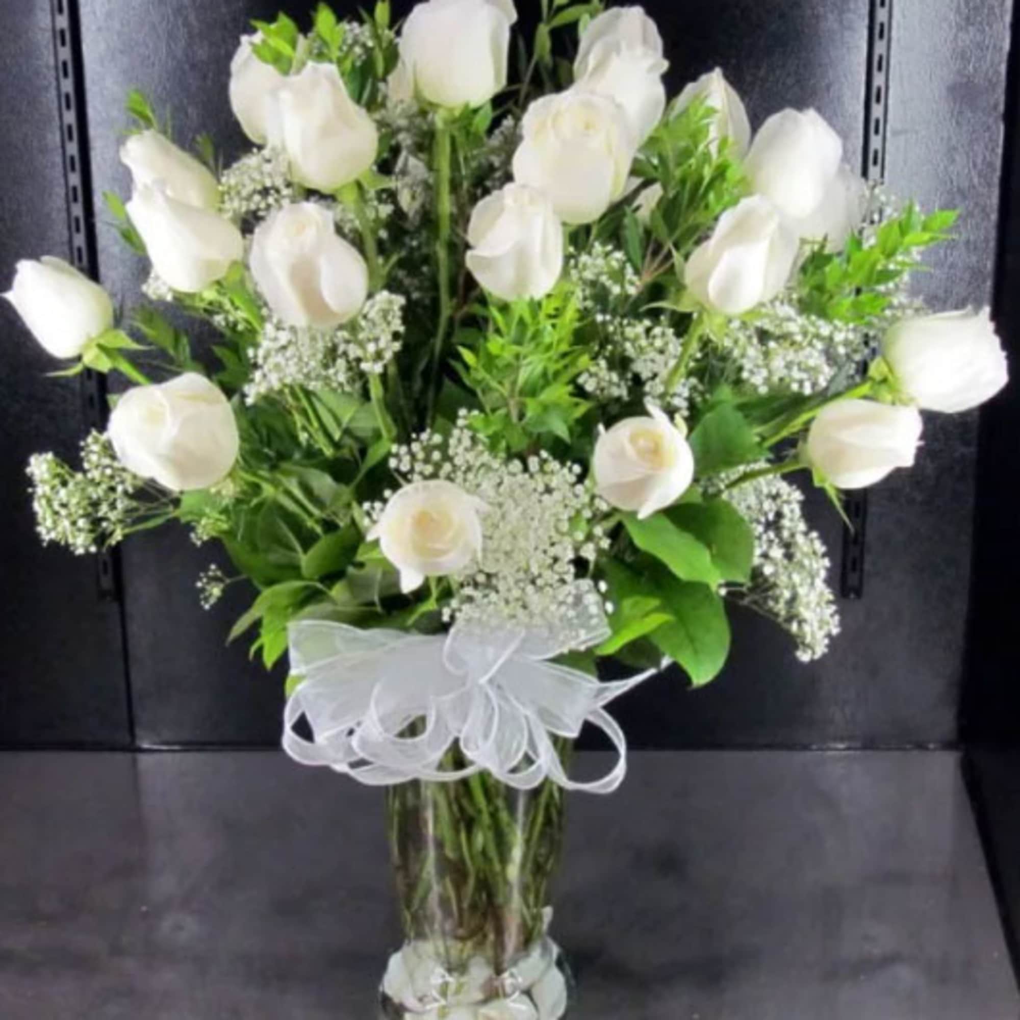 White rose bouquet in a clear glass vase with a white ribbon