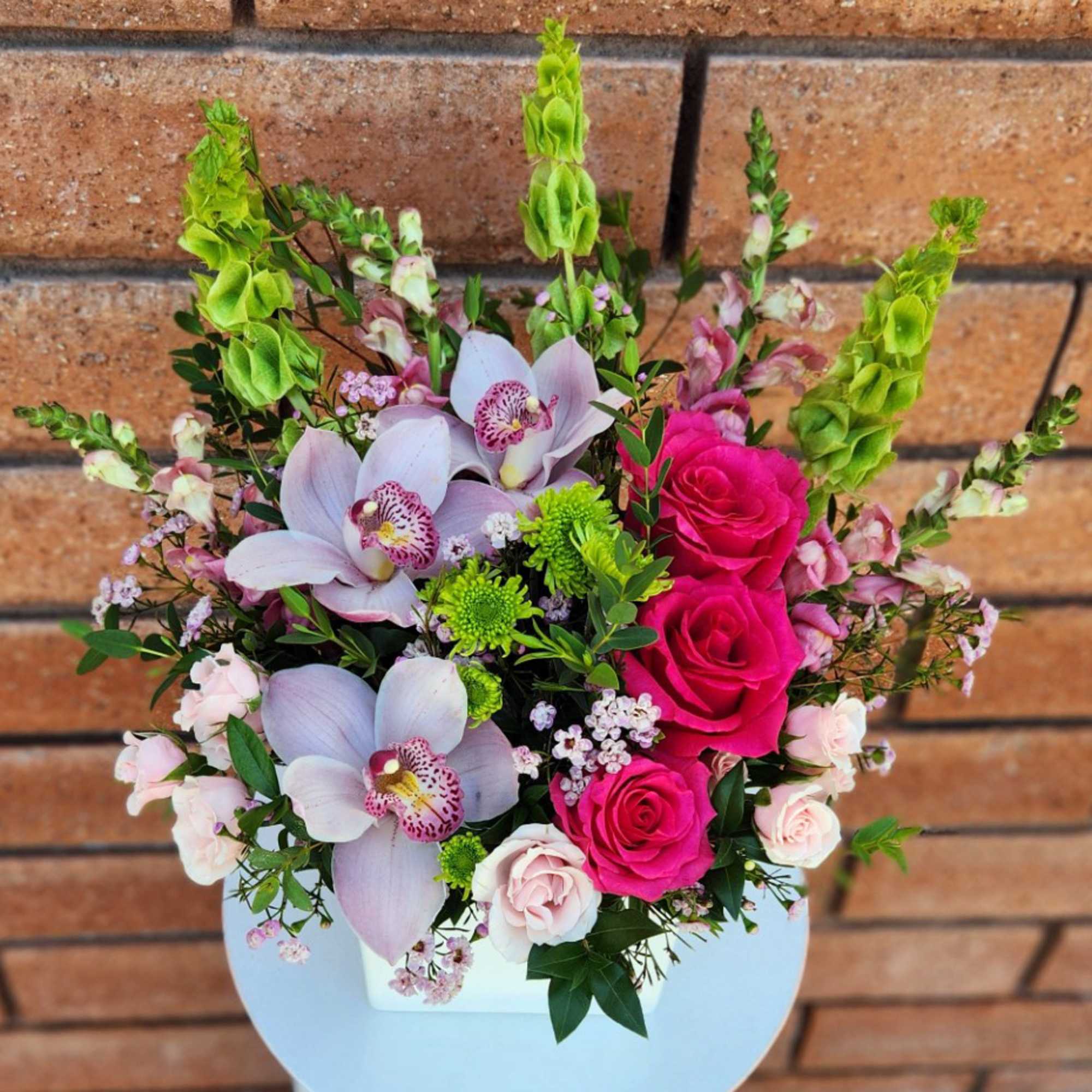 Pink roses and pale orchids arranged in a white container