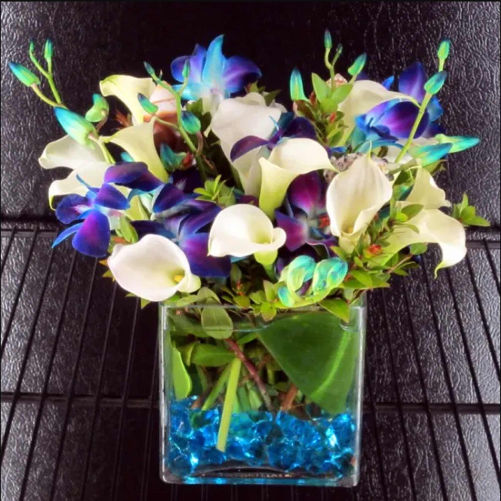 Bouquet of white and purple calla lilies in a clear square vase