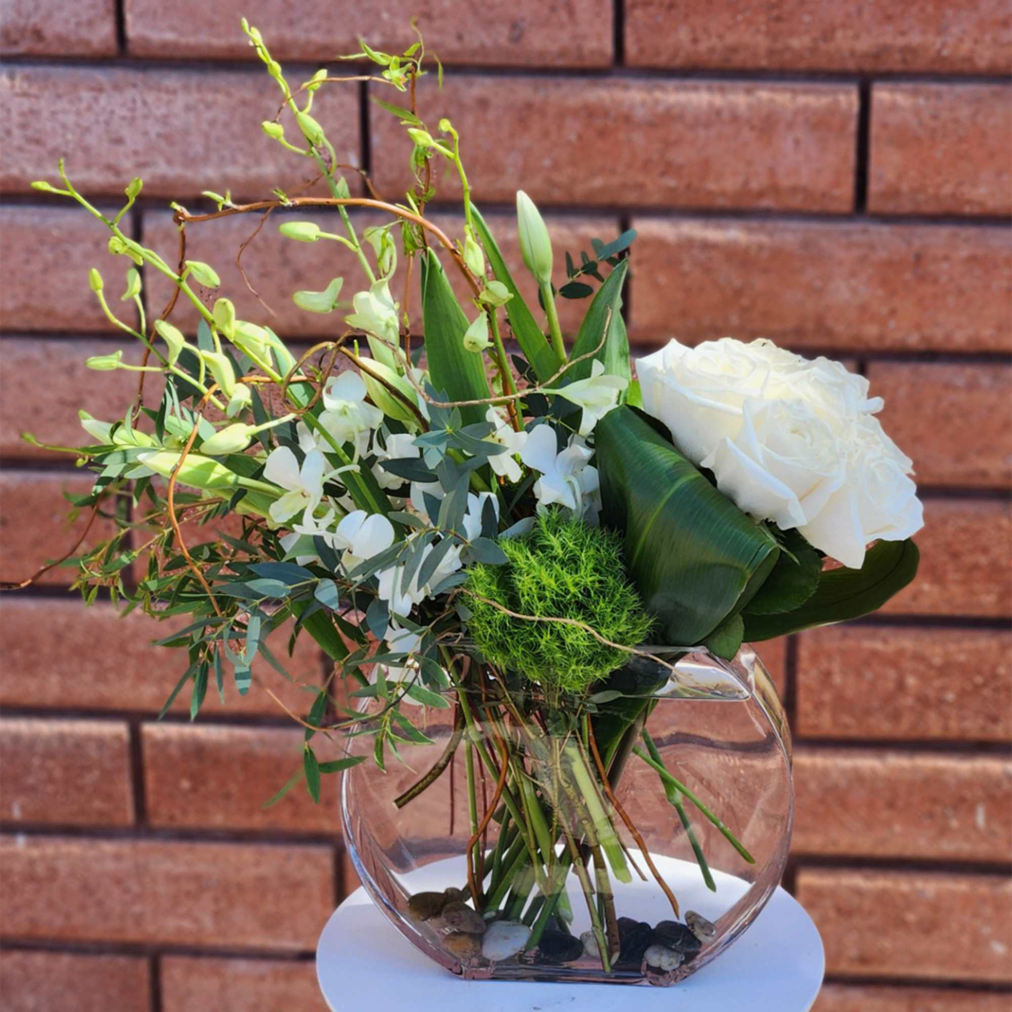 White rose arrangement in a clear glass vase with airy greenery
