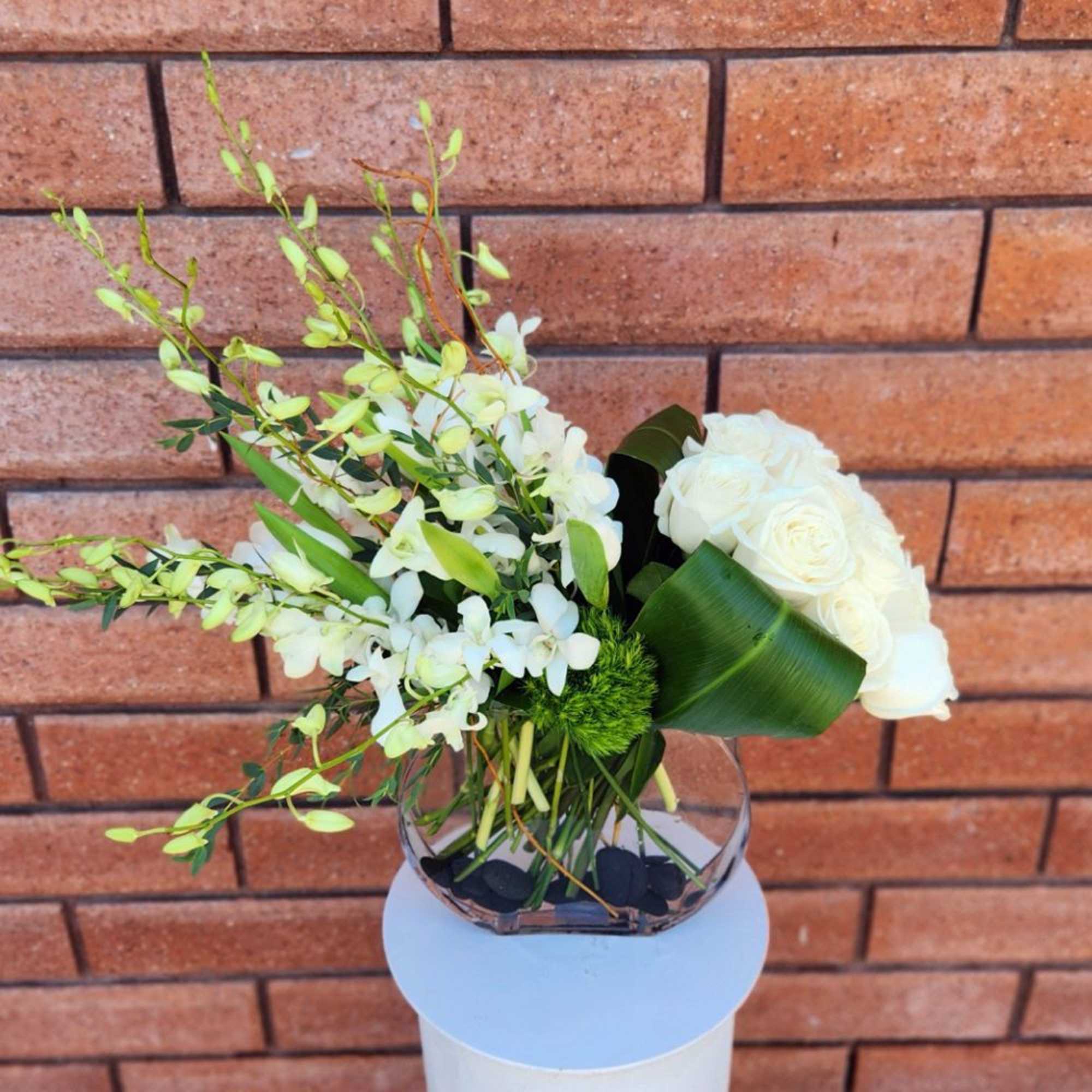 White rose and orchid arrangement in a glass vase
