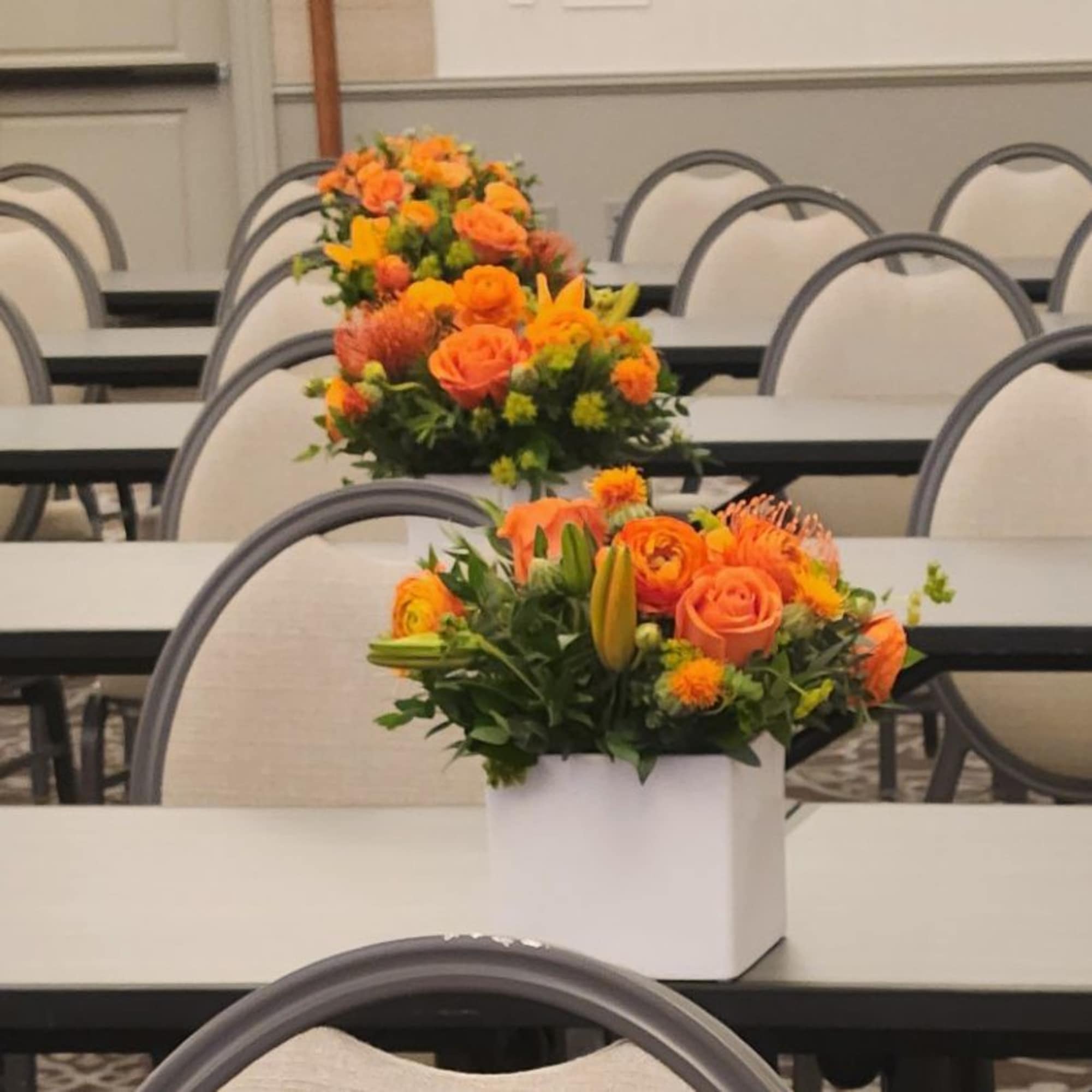 Orange floral centerpiece in a white box on a table