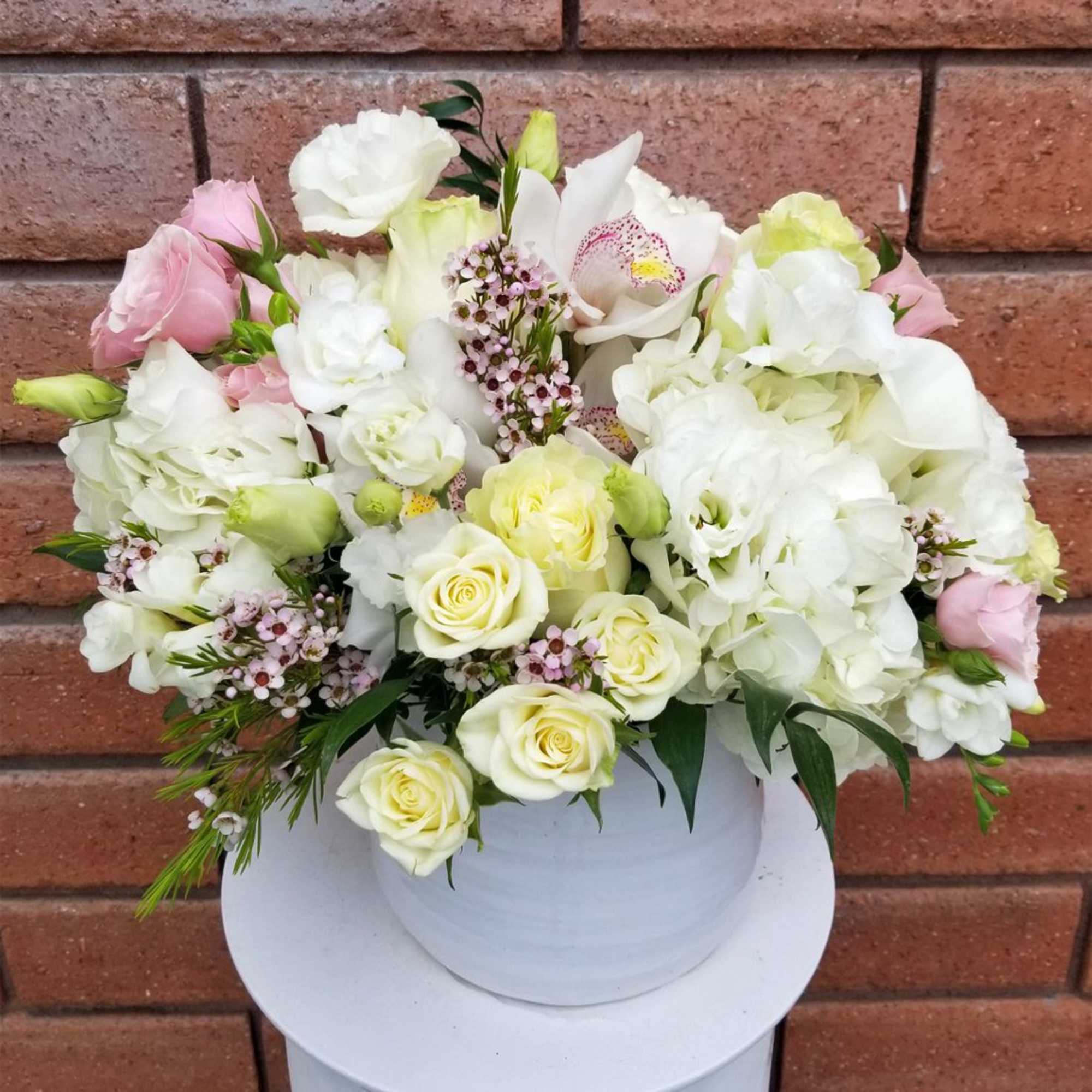 White and pale pink floral arrangement in a white vase