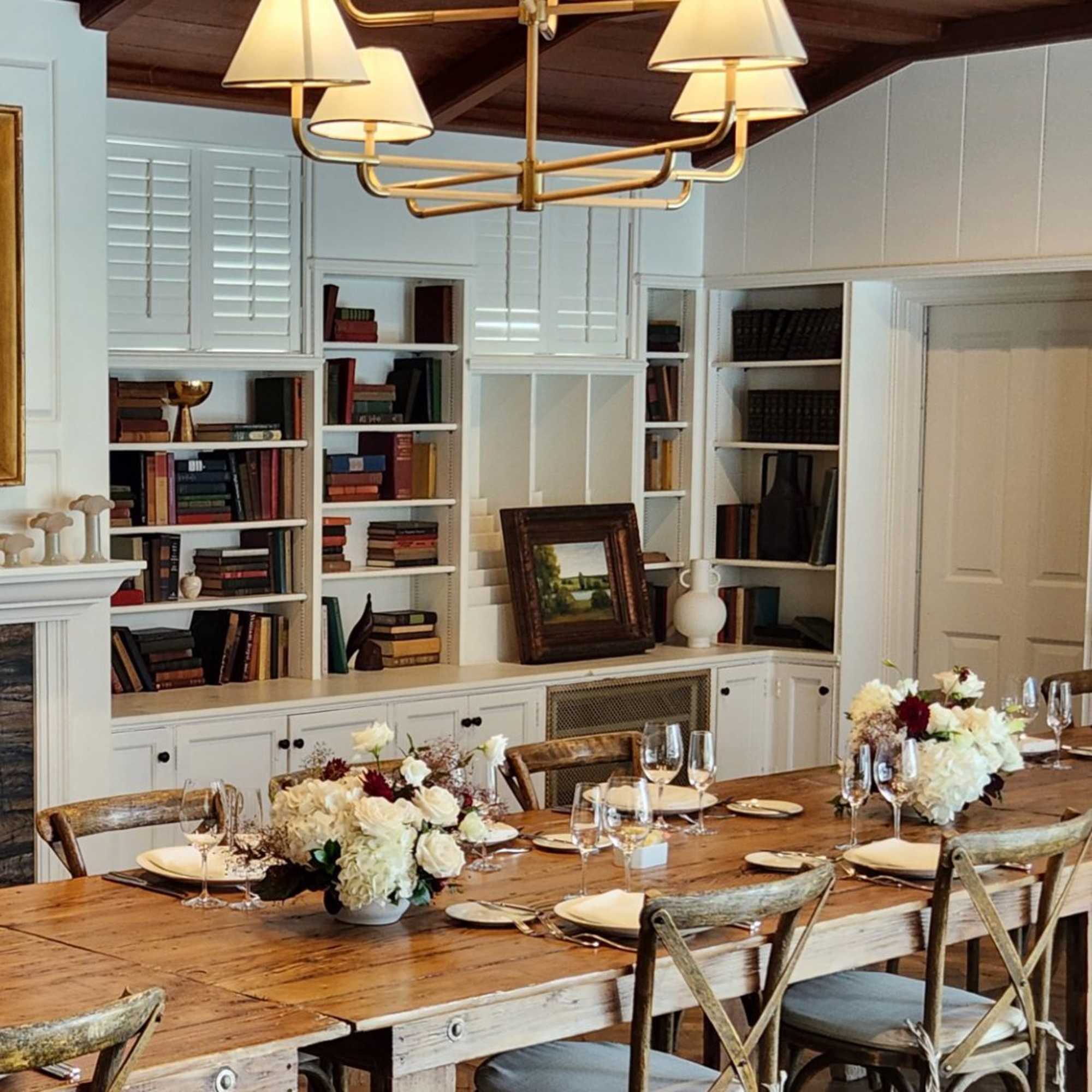 Dining table with white floral centerpieces and place settings in a room