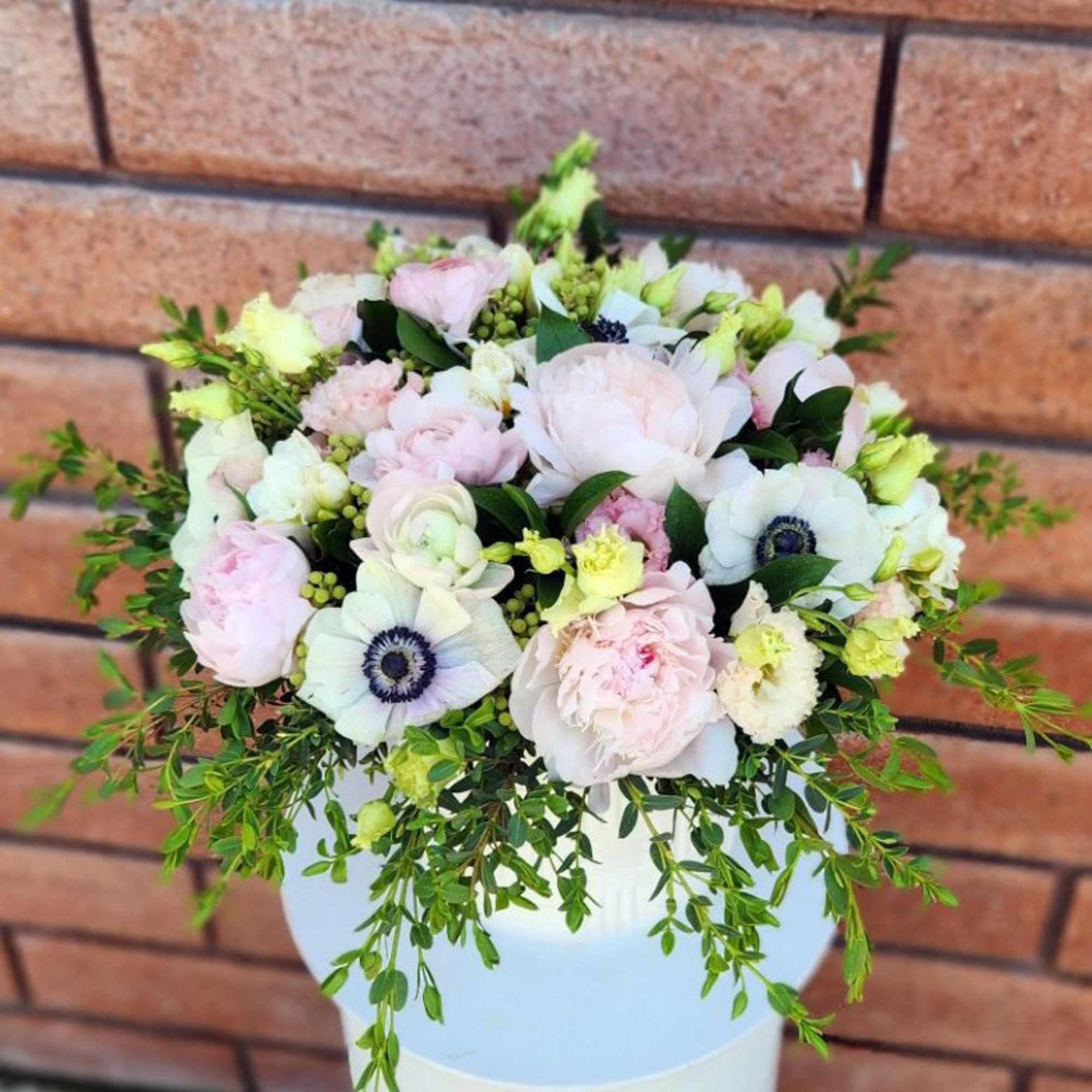 Round bouquet of pale pink and white flowers in a white vase