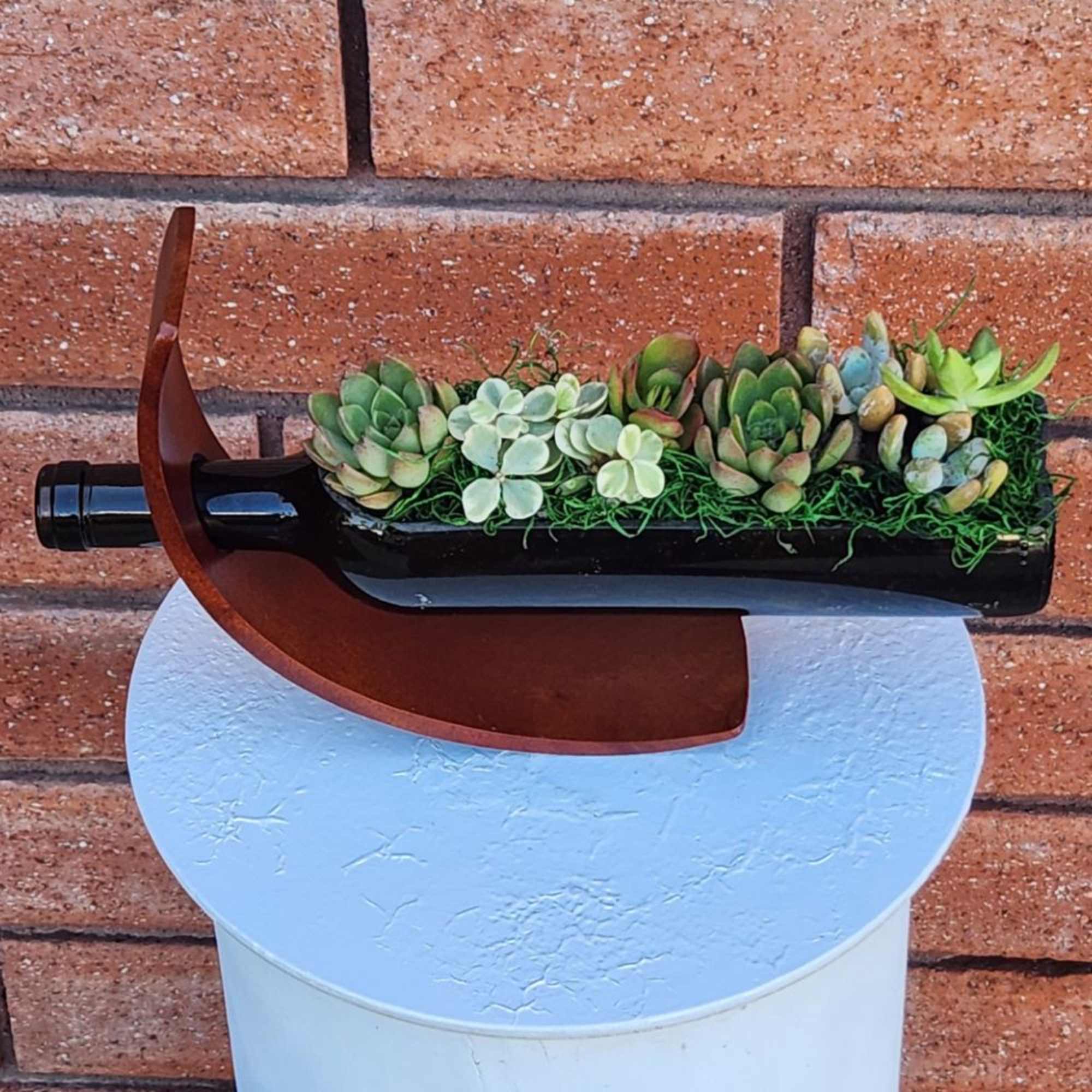 Succulent arrangement in a wine bottle planter on a white stand