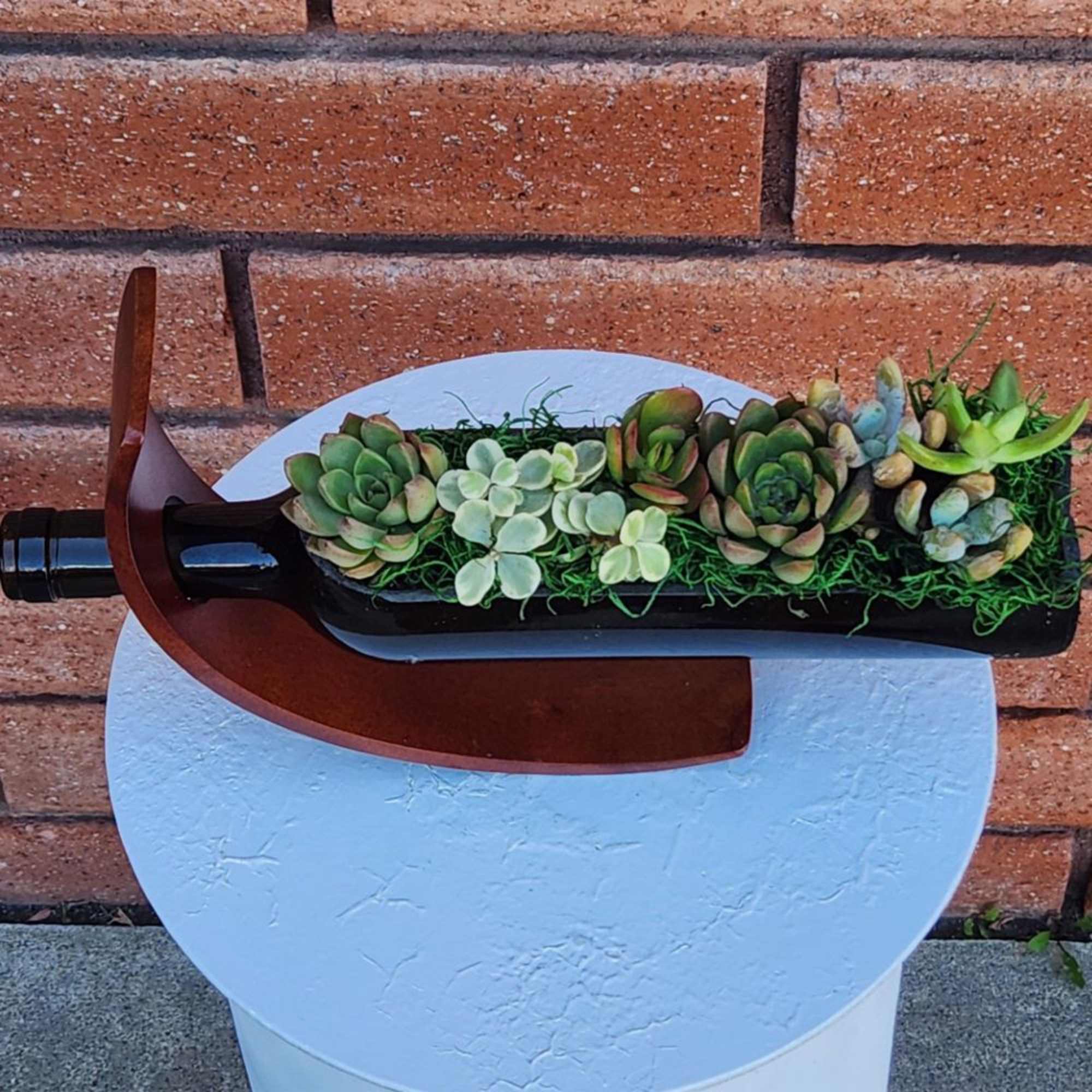 Succulent arrangement in a wine bottle planter on a round stand
