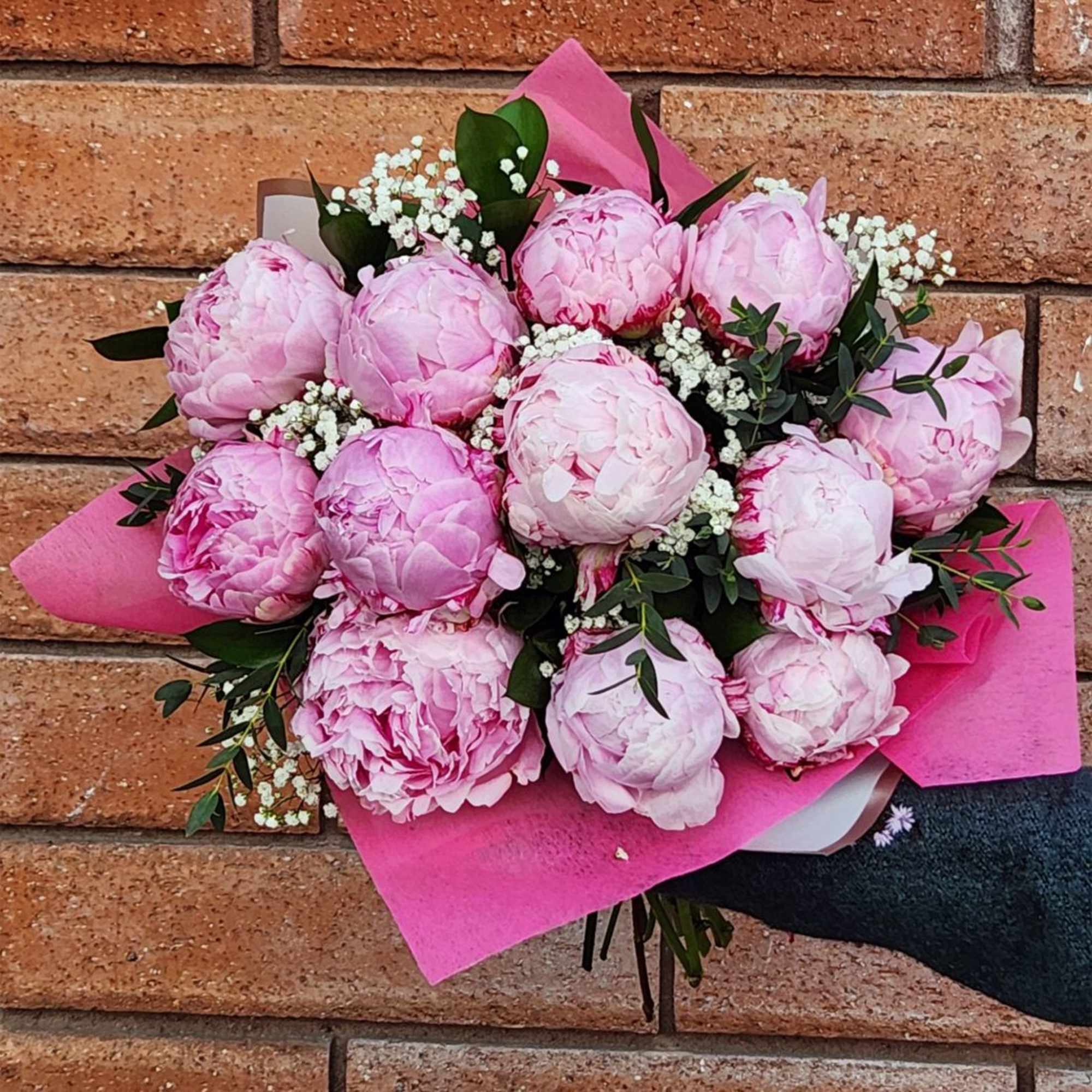 Bouquet of pink peonies with white filler flowers and pink wrapping