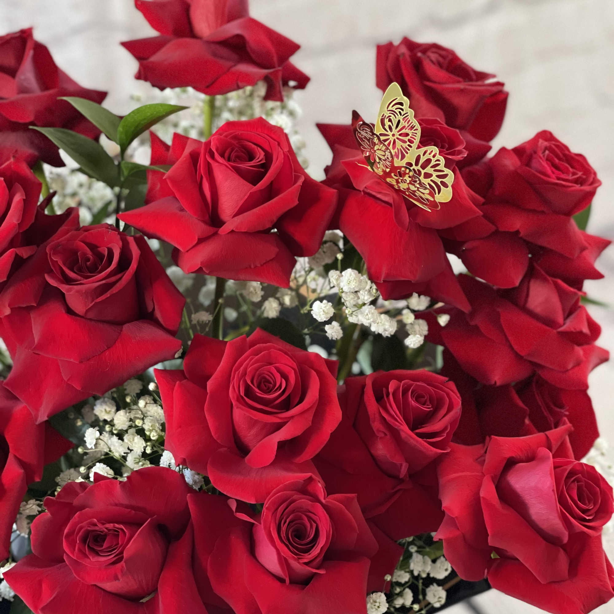 Bouquet of red roses with baby's breath and a butterfly accent