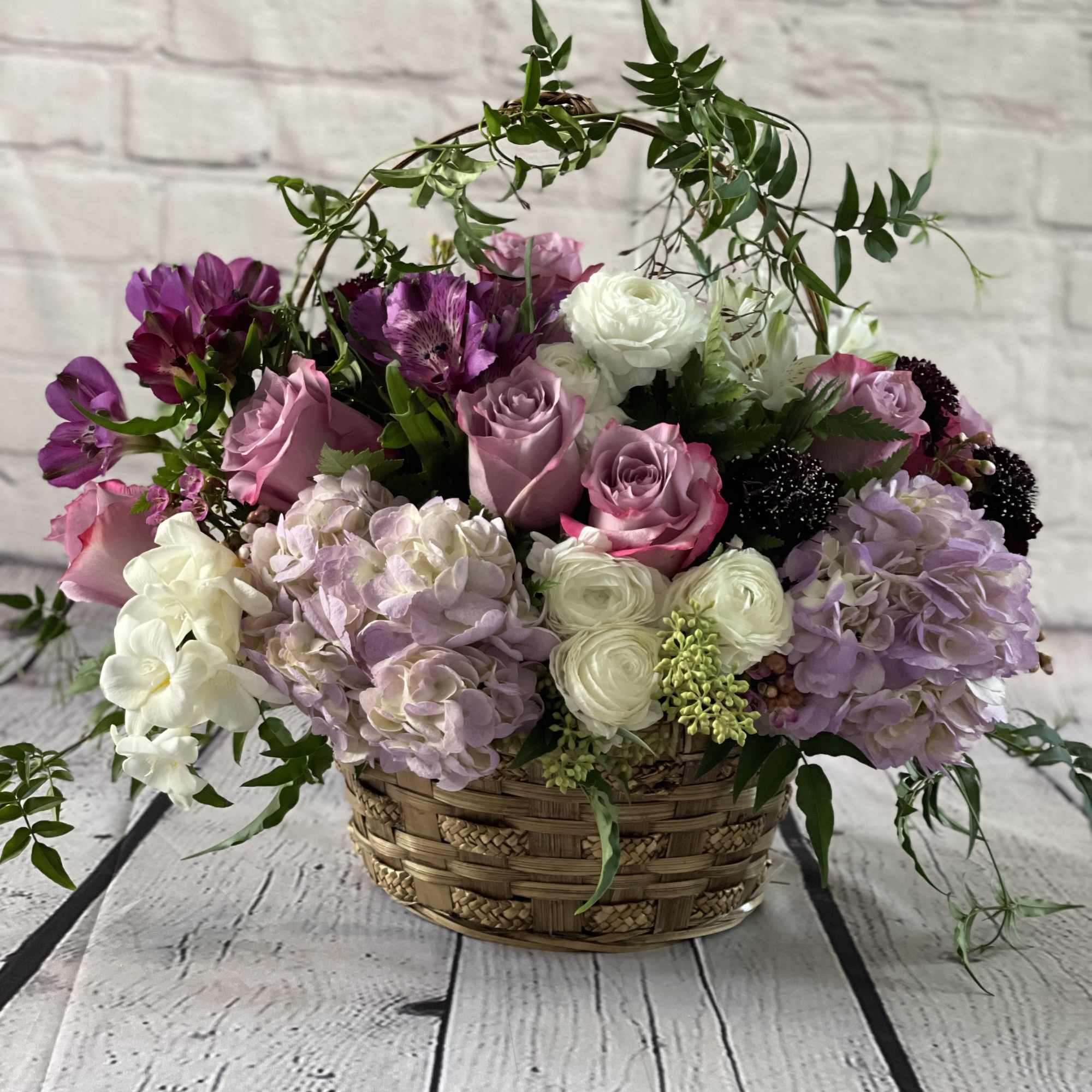 Basket arrangement of pink, white, and purple flowers