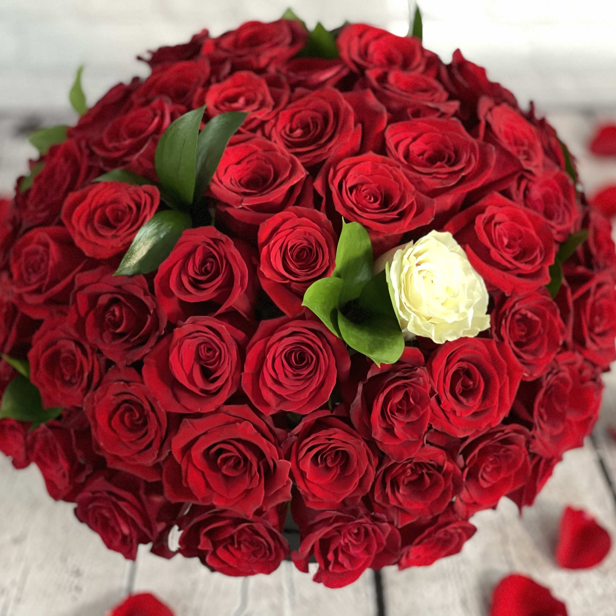 Round bouquet of red roses with one white rose