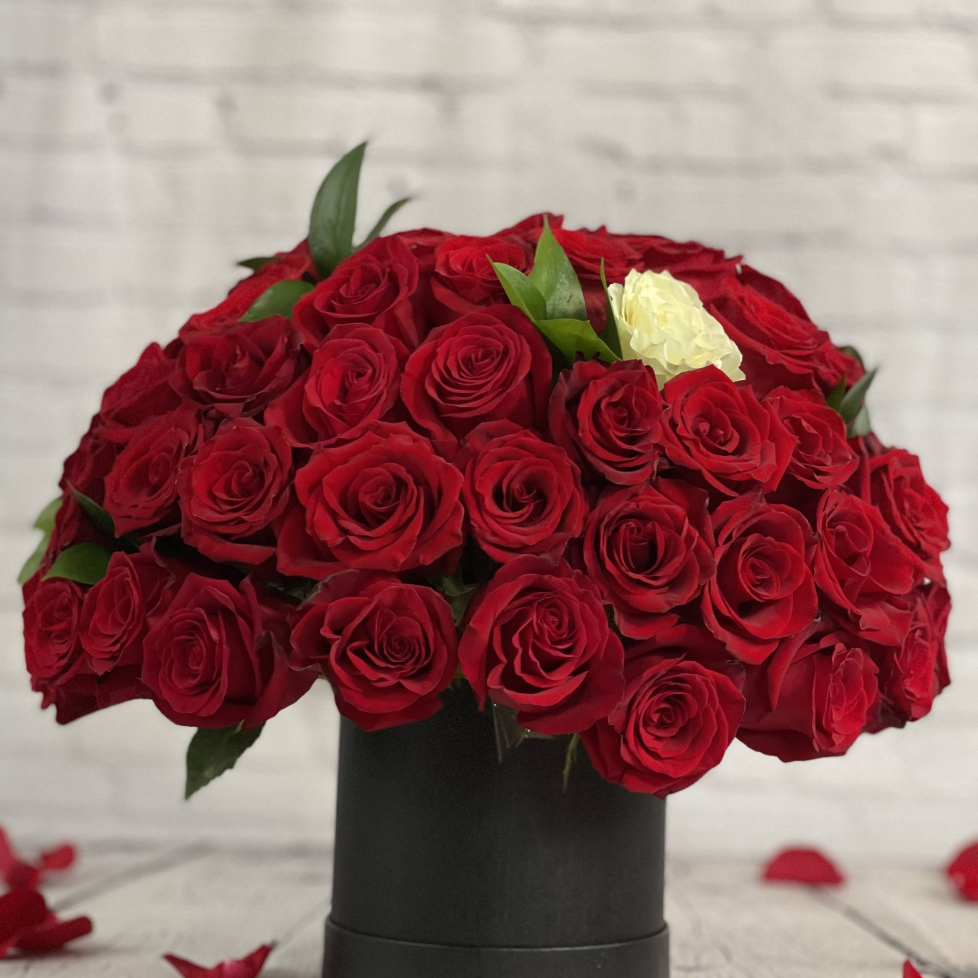 Large bouquet of red roses in a black box with a few white roses