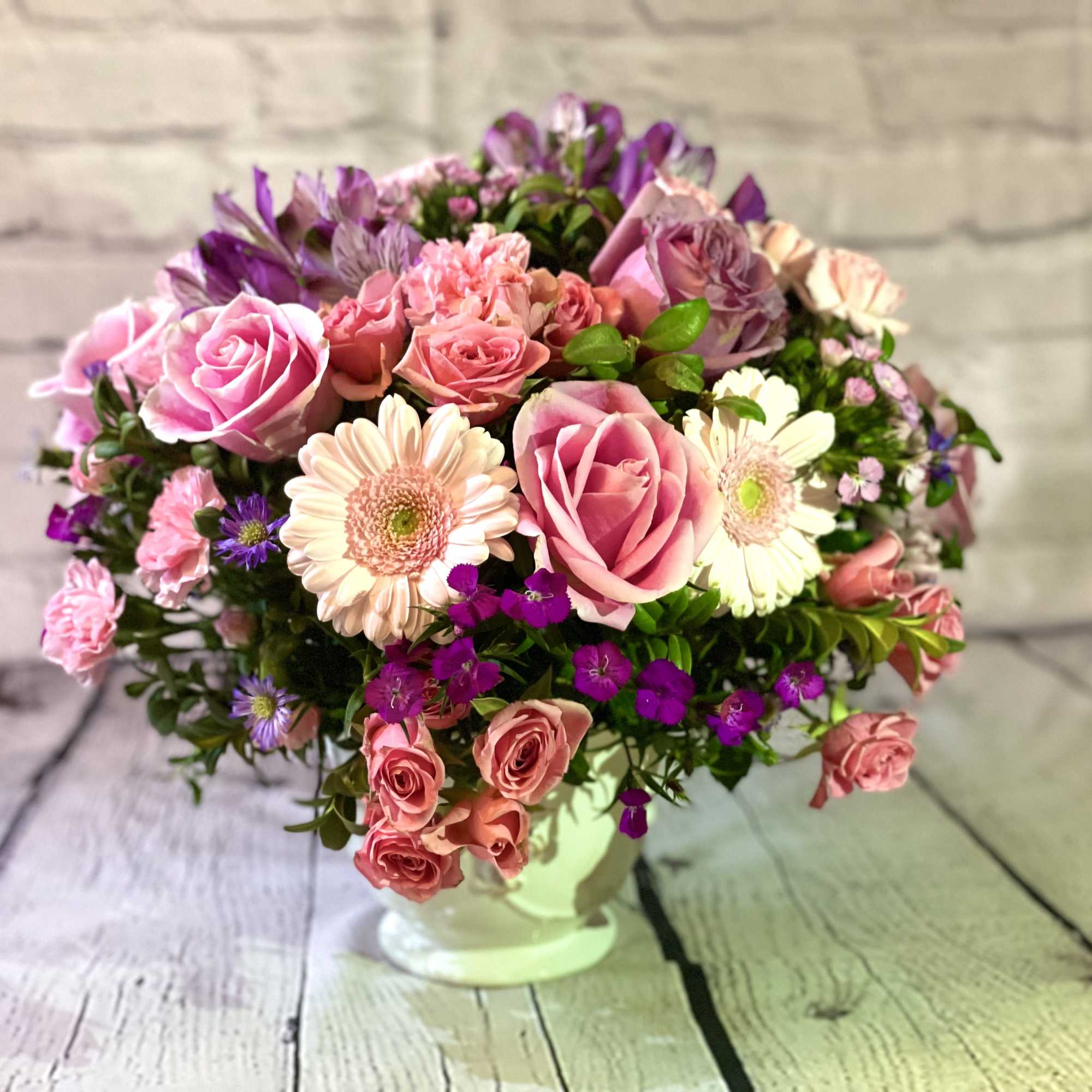 Pink and purple mixed flower arrangement in a white vase