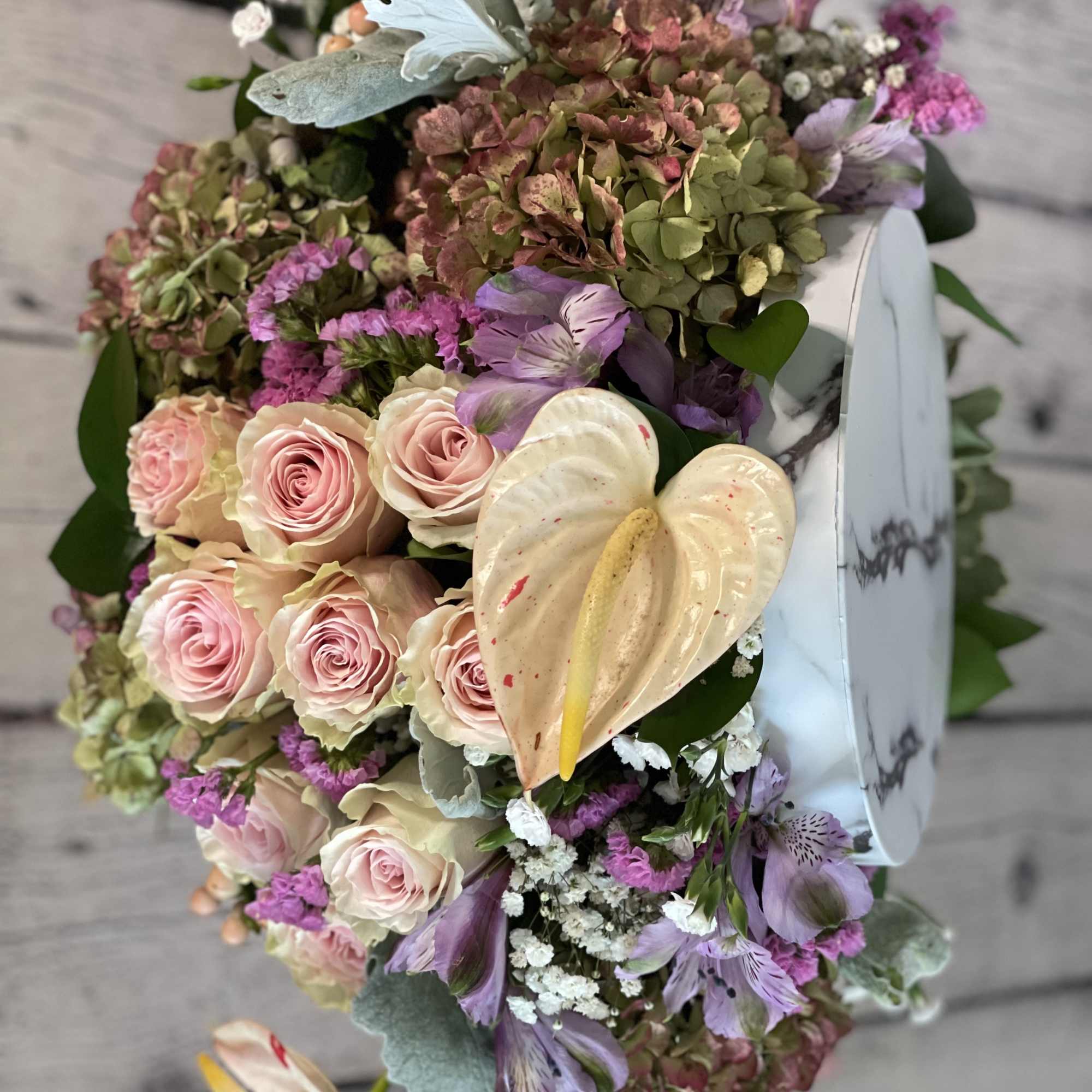 Bouquet of pink roses, purple flowers, and cream anthuriums