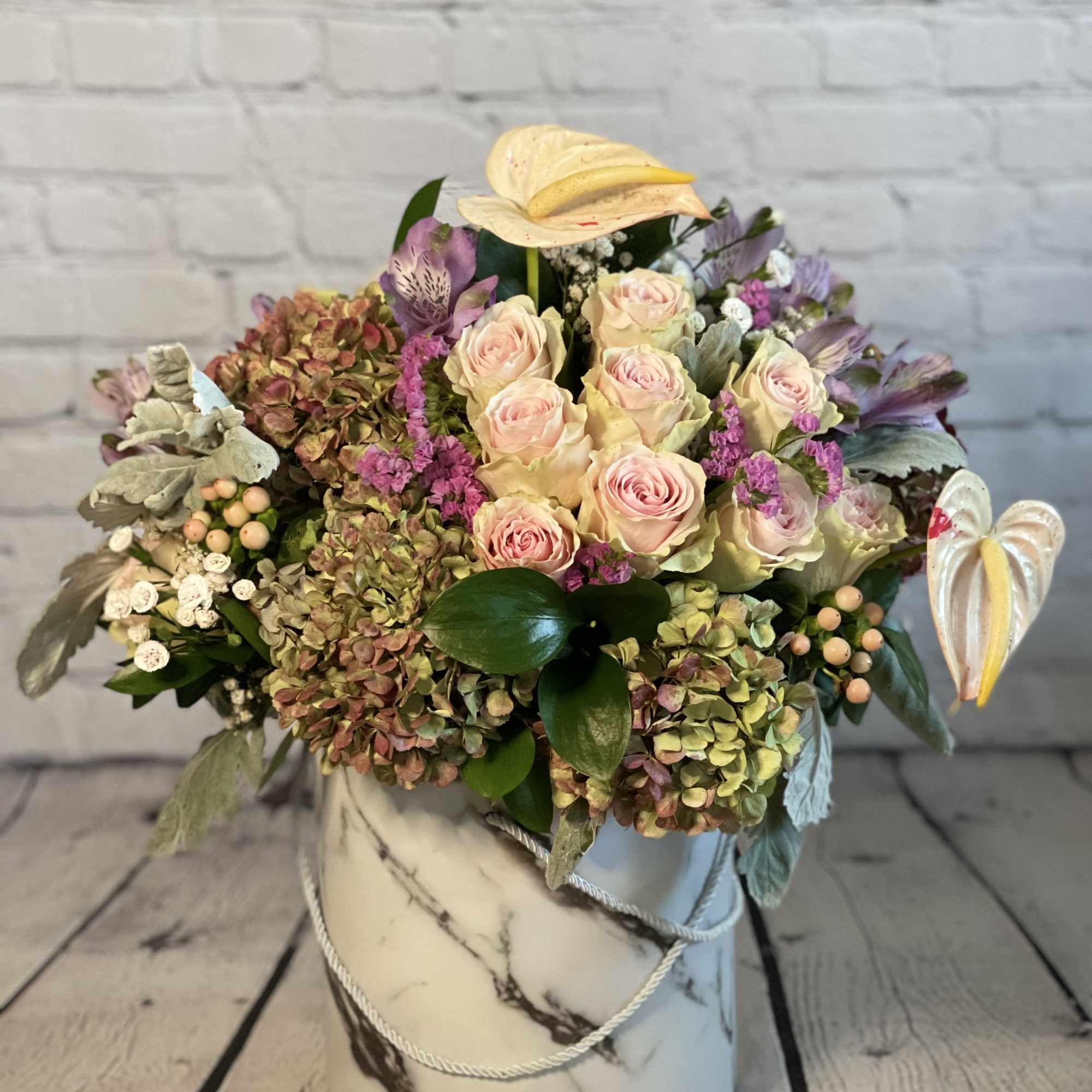 Bouquet of pale pink roses and hydrangeas in a marble-patterned hat box