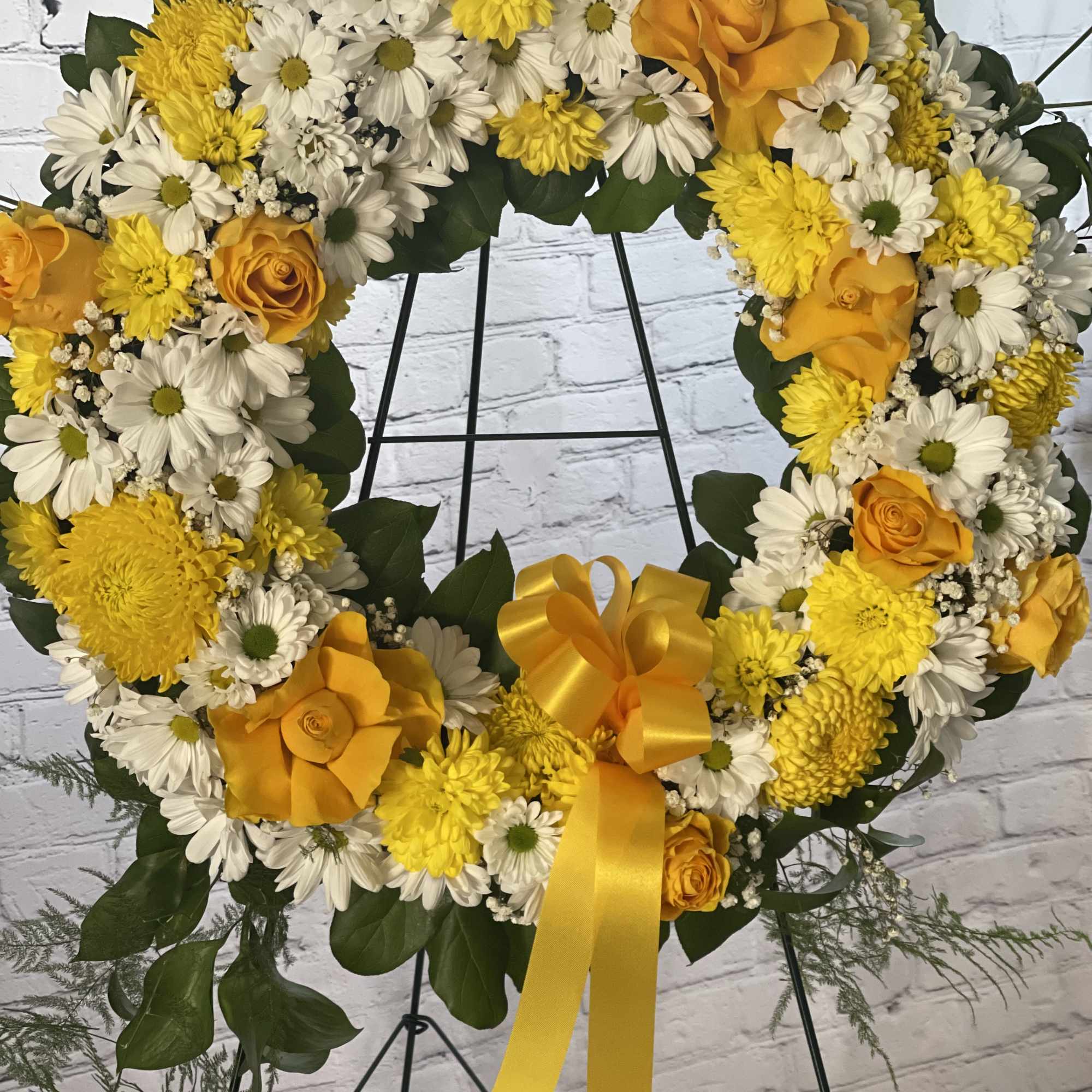 Yellow and white floral wreath with roses on a stand