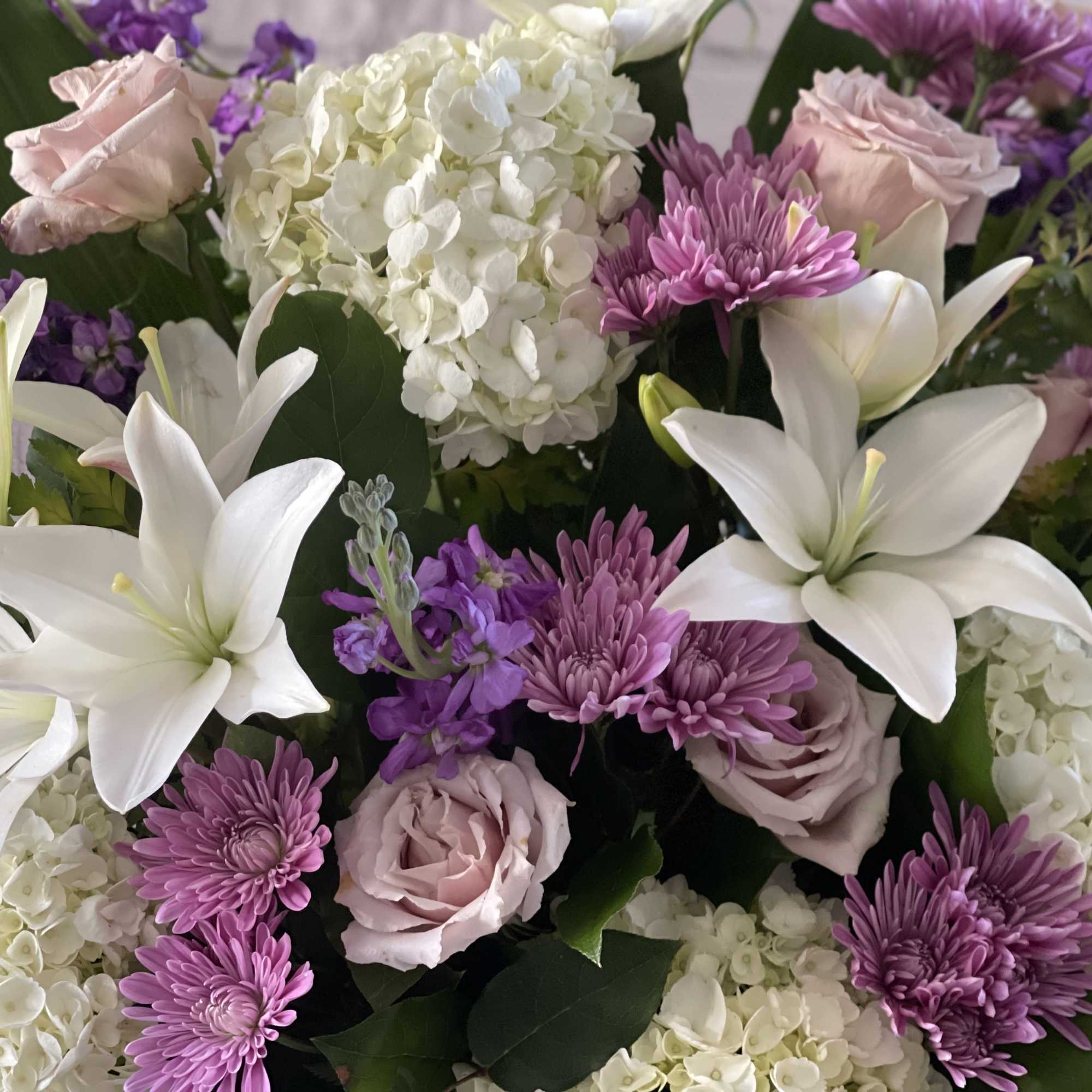 Bouquet of white lilies, pink roses, purple mums, and white hydrangeas
