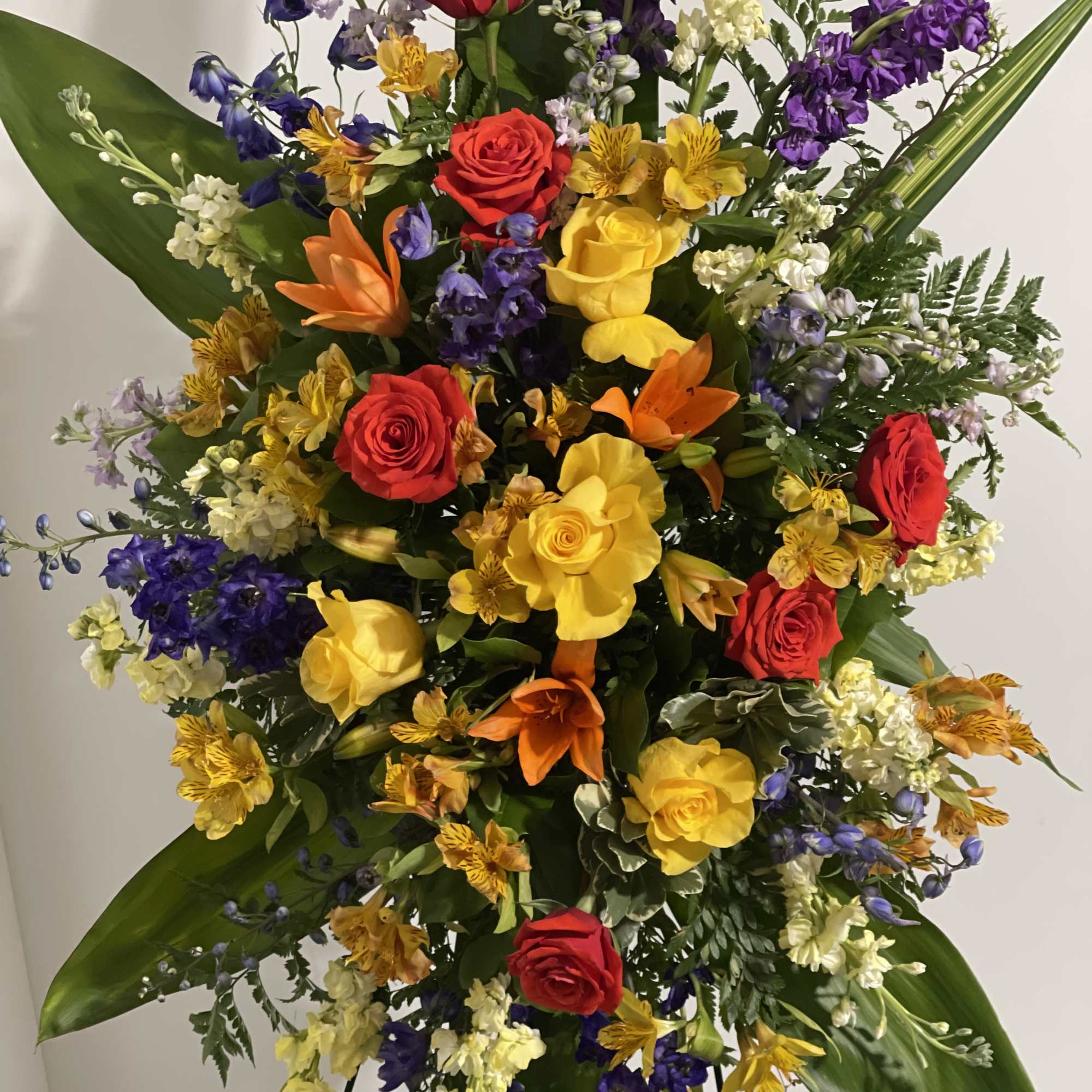 Large standing floral spray with red, yellow, orange, and purple blooms