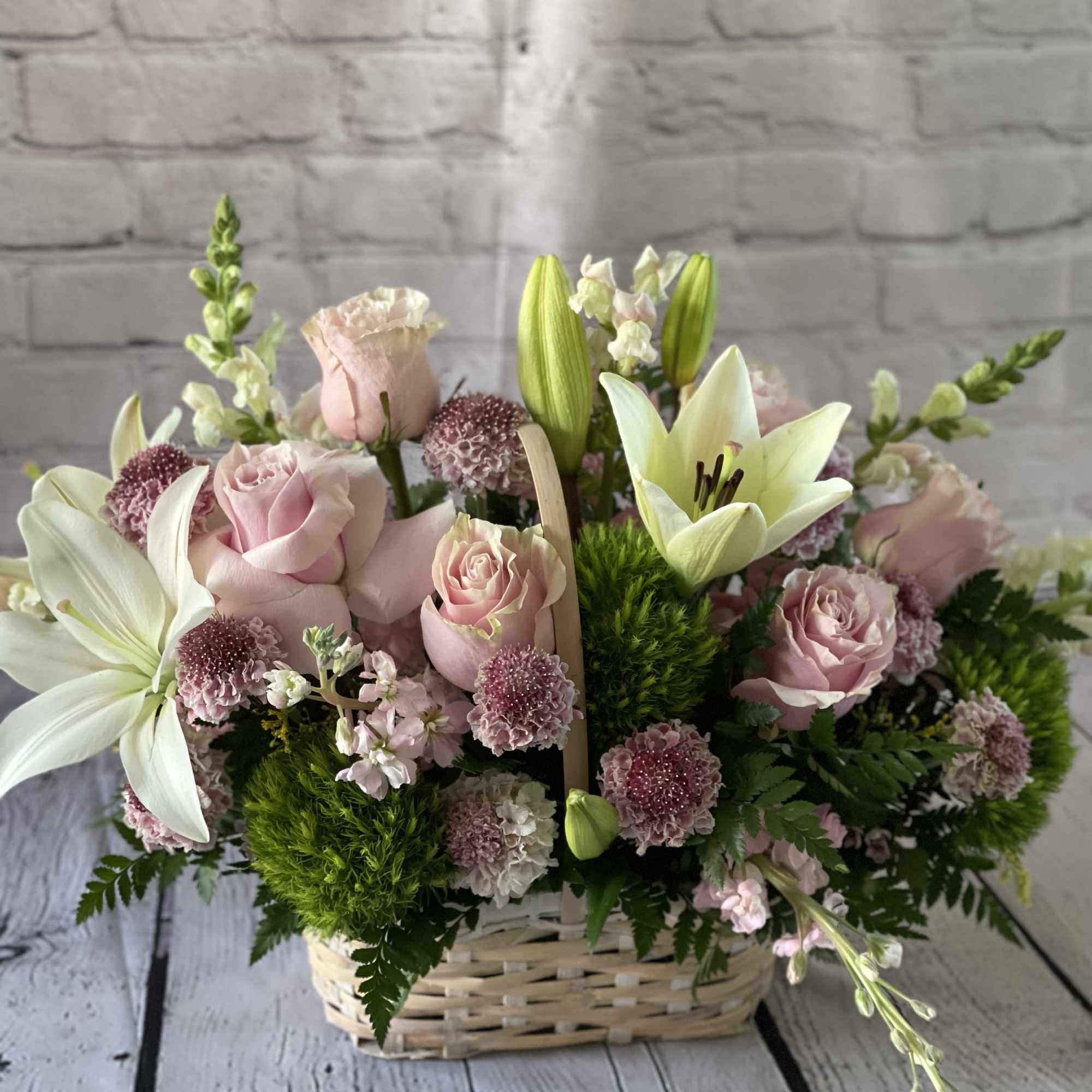 Pink roses and white lilies arranged in a wicker basket