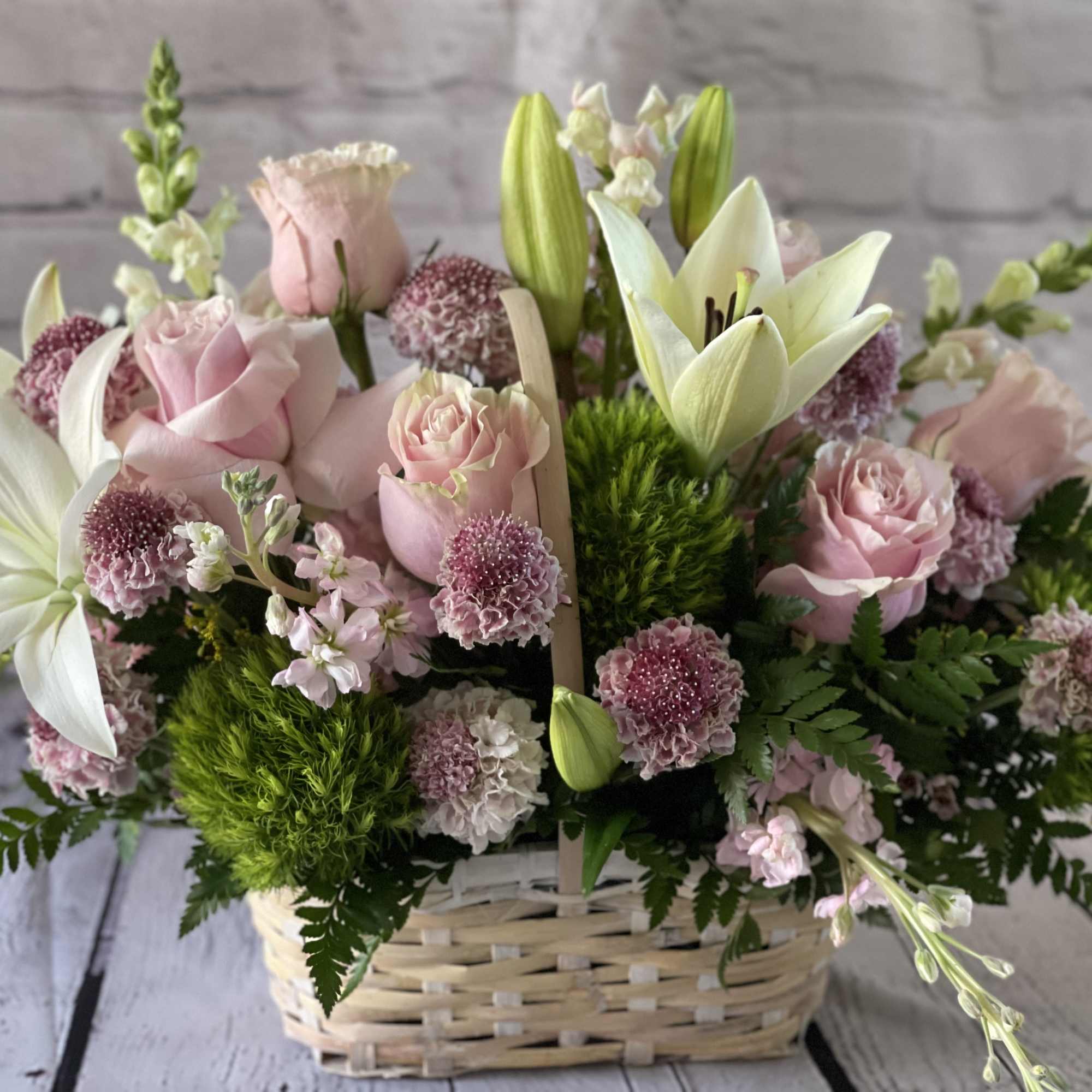 Pink roses and white lilies arranged in a wicker basket