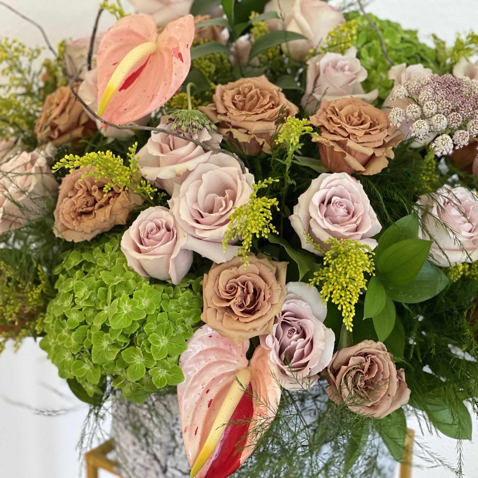 Bouquet of blush and tan roses with pink anthuriums and green hydrangea
