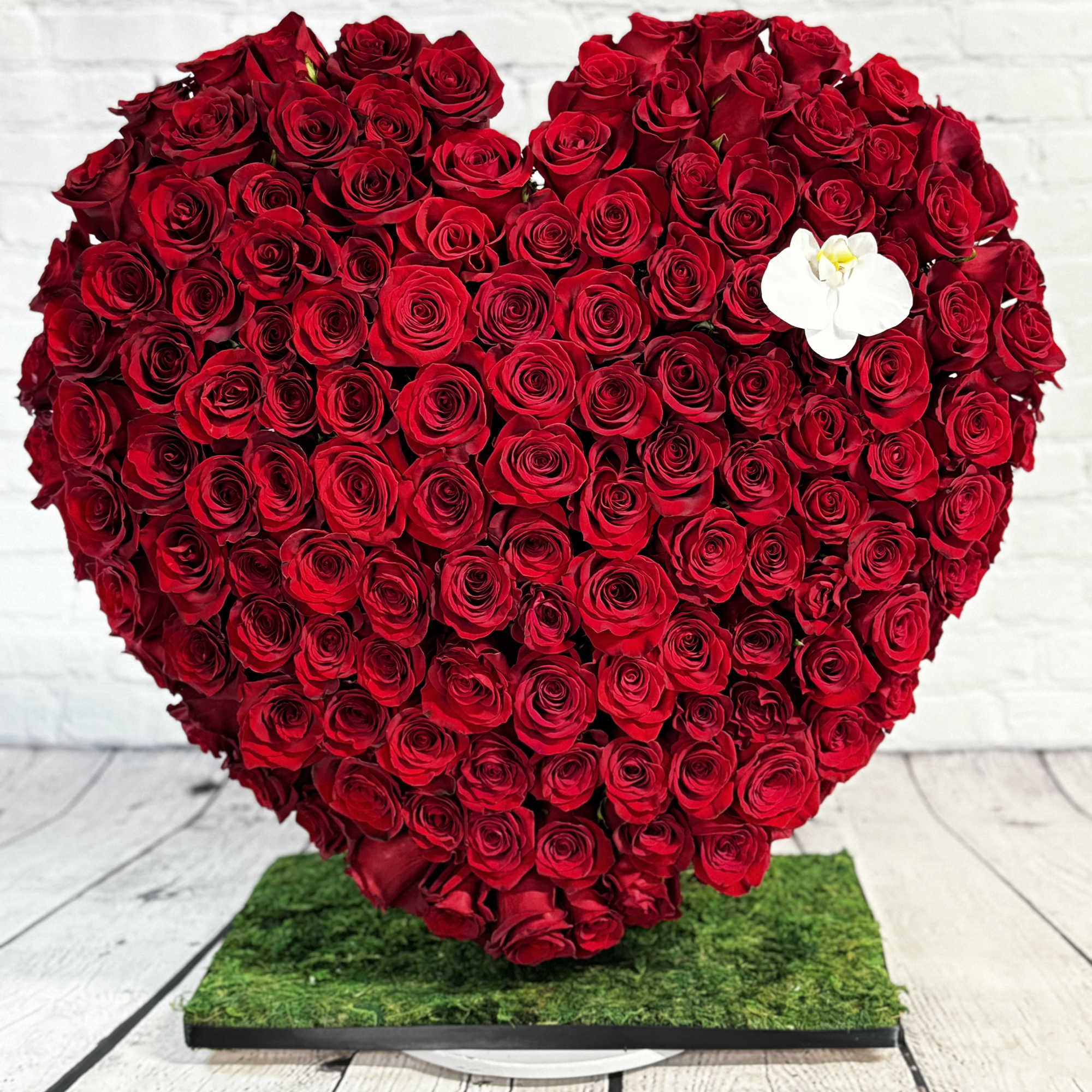 Heart-shaped arrangement of red roses with a white orchid accent, photo 2 of 4