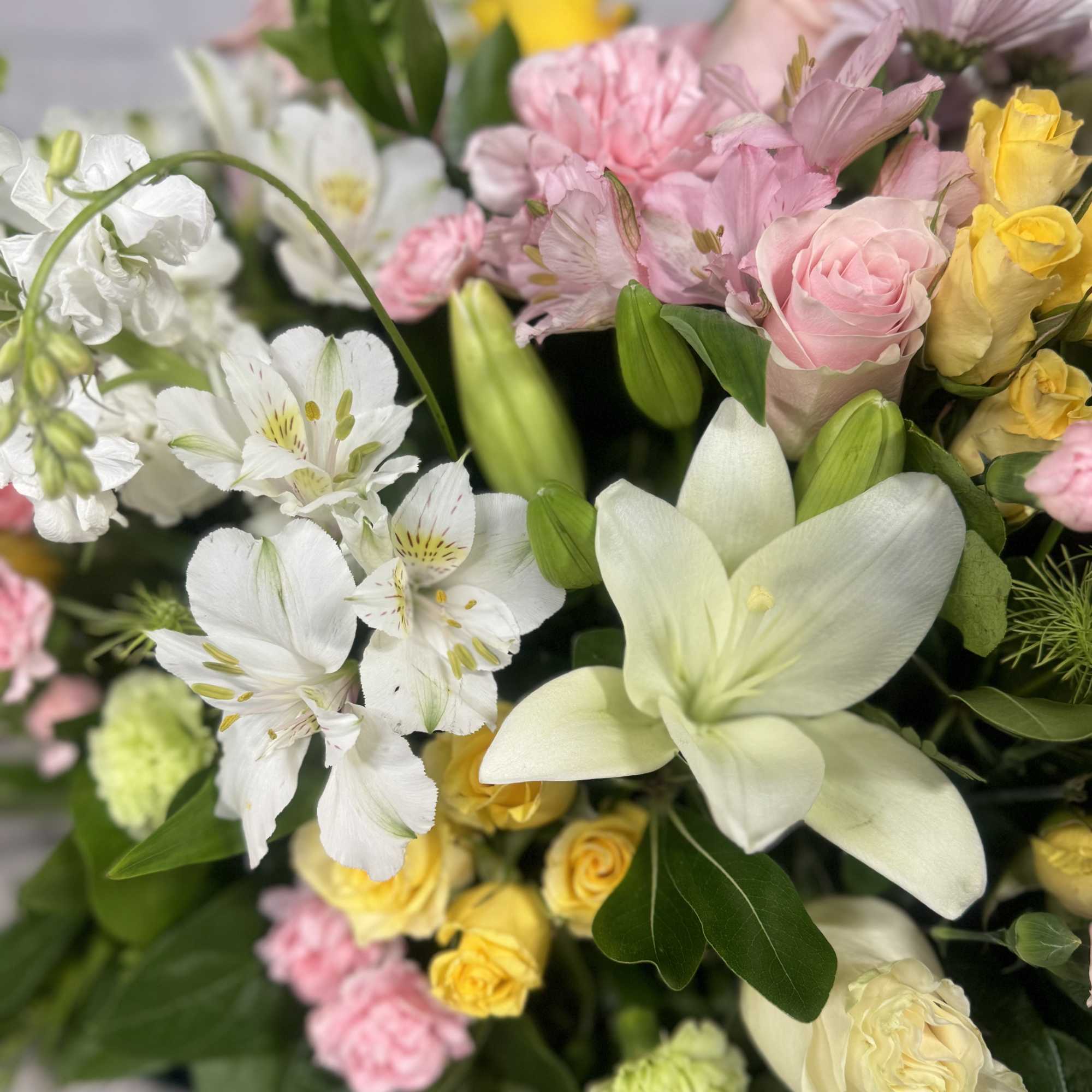 Mixed bouquet with pink and yellow roses, white lilies, and white alstroemeria