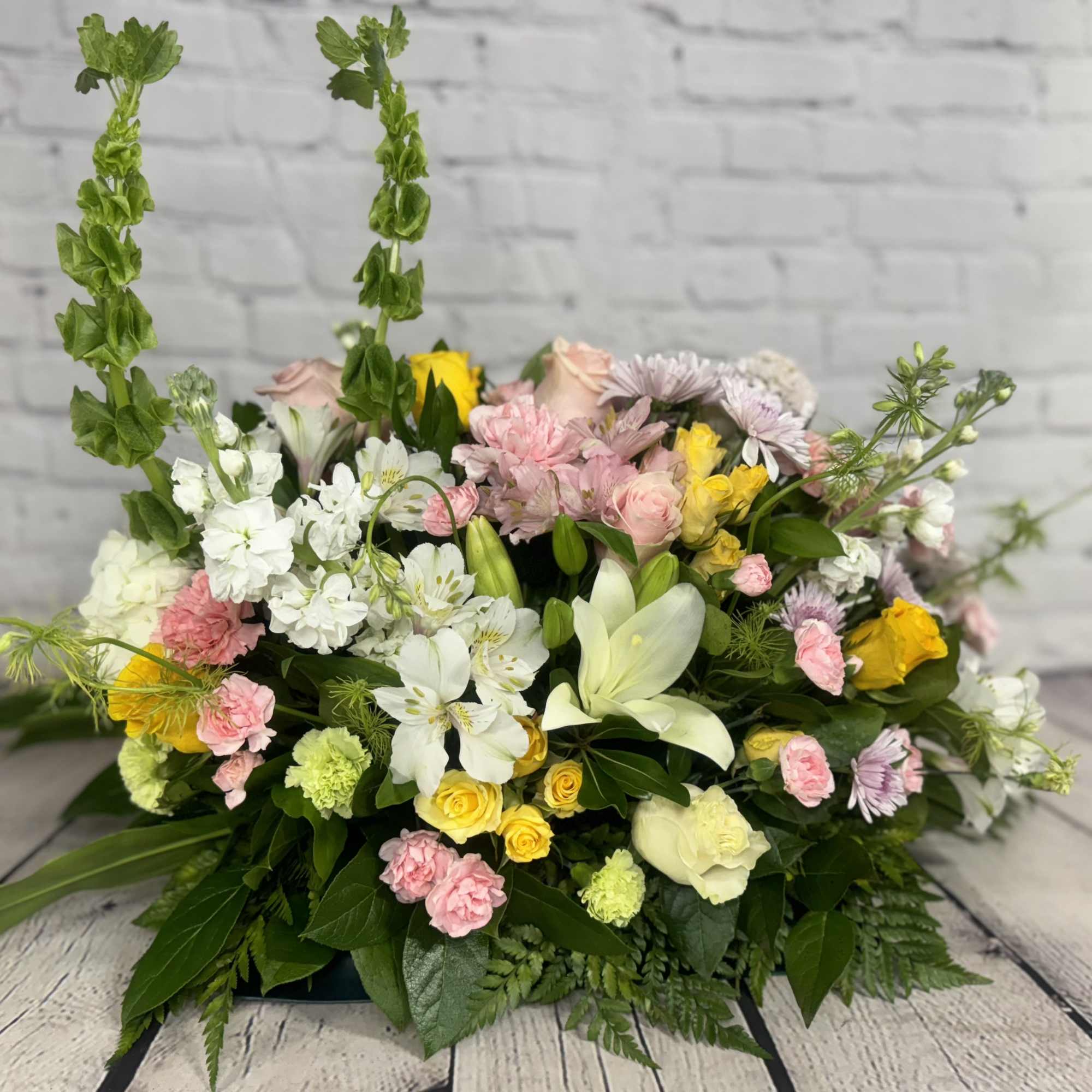 Mixed bouquet with white lilies, pink and yellow flowers, and tall green spikes