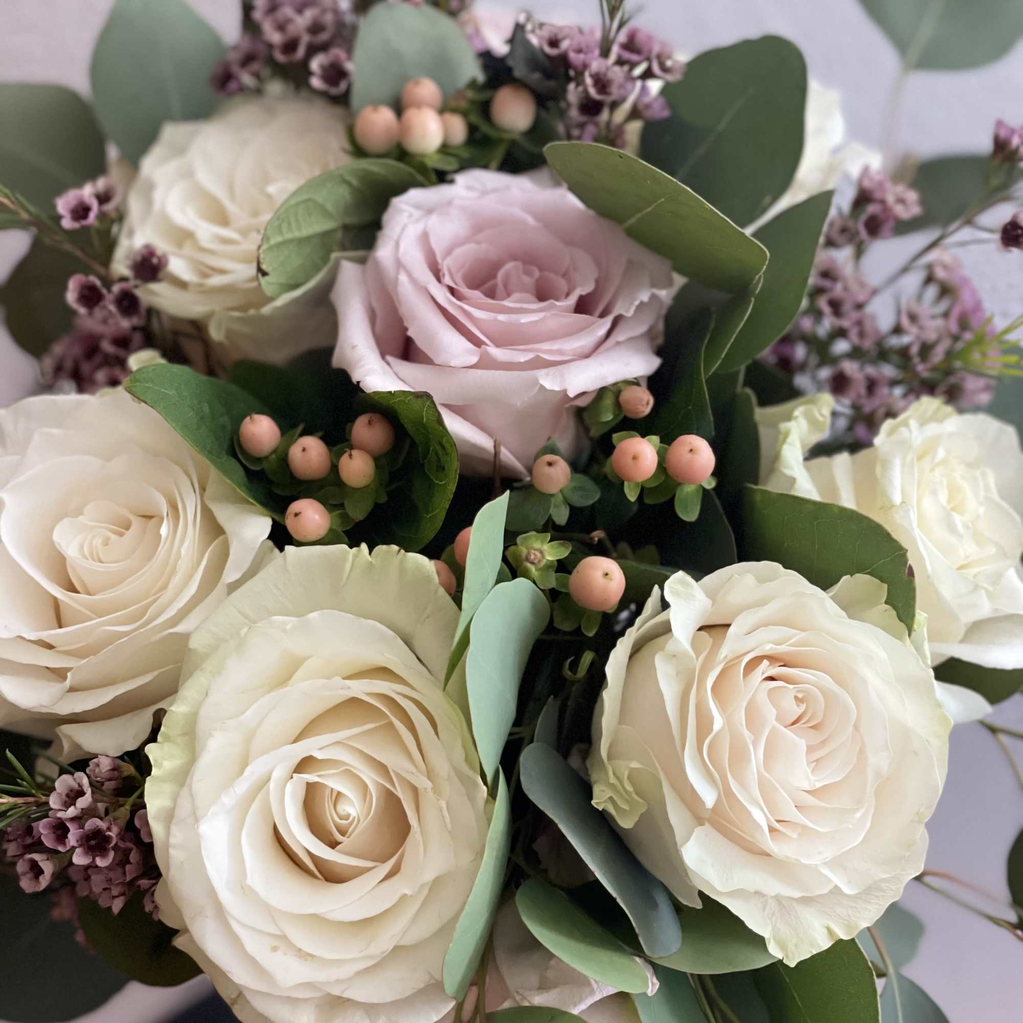 Bouquet of cream and blush roses with eucalyptus and small purple filler flowers