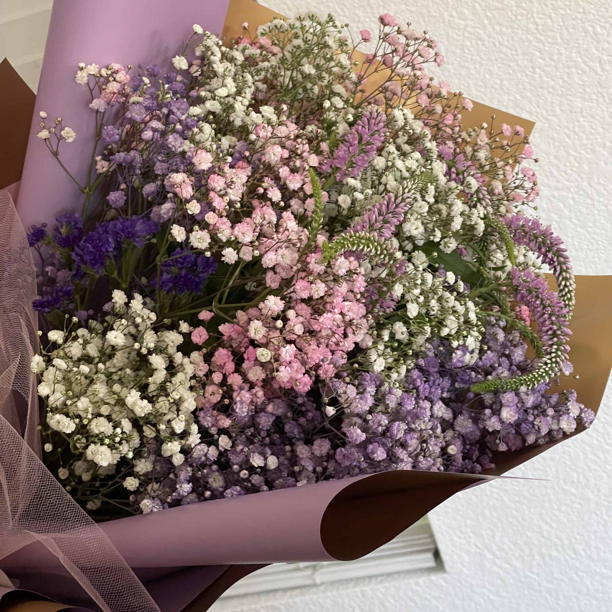 Bouquet of pink, purple, and white baby's breath wrapped in lavender paper