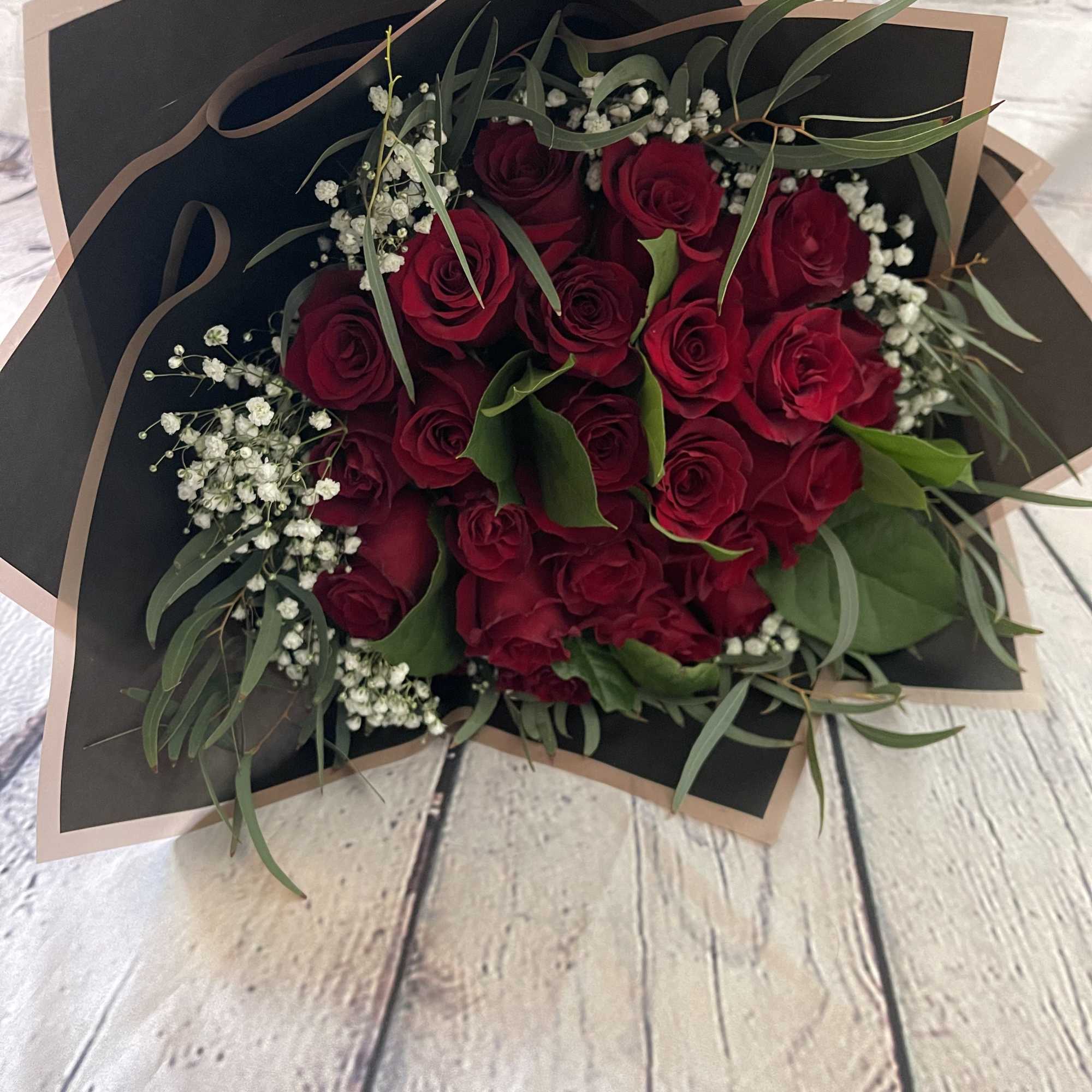 Bouquet of red roses with baby's breath and greenery in black wrap