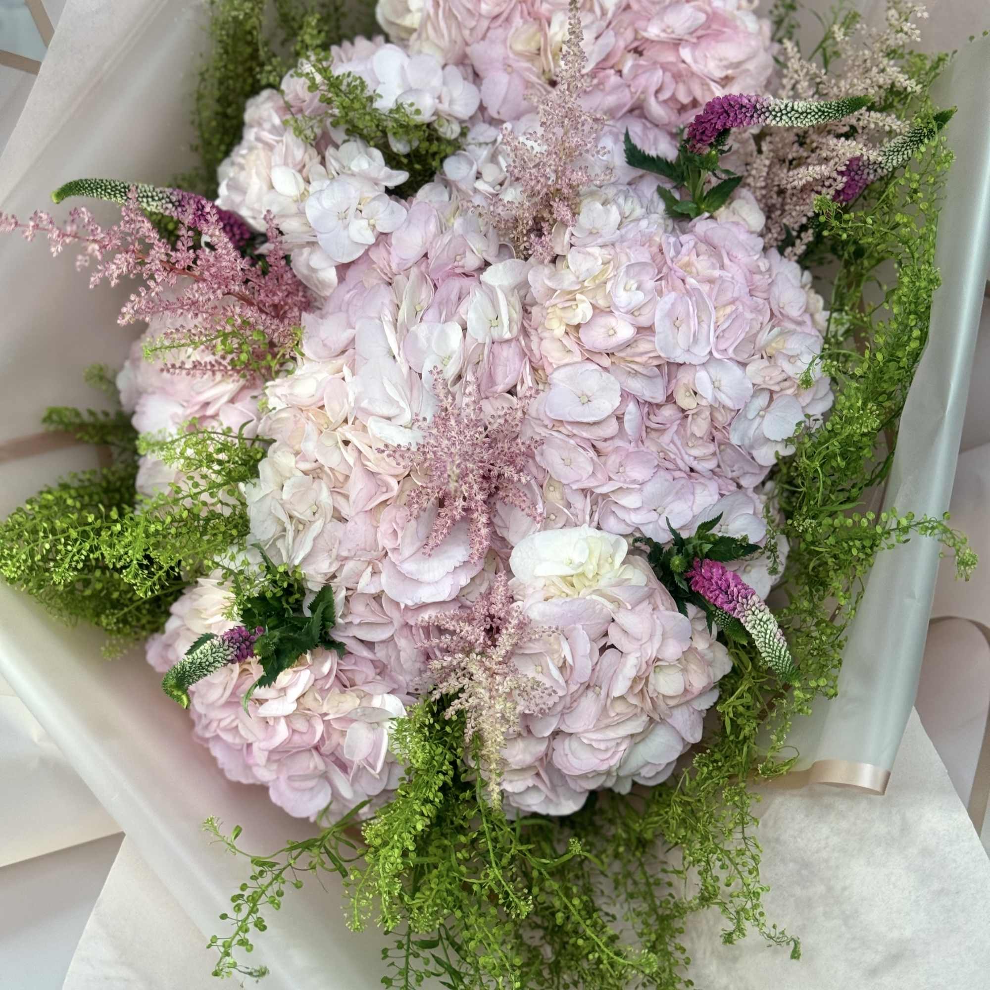 Pink hydrangea bouquet with green filler and pale wrapping paper