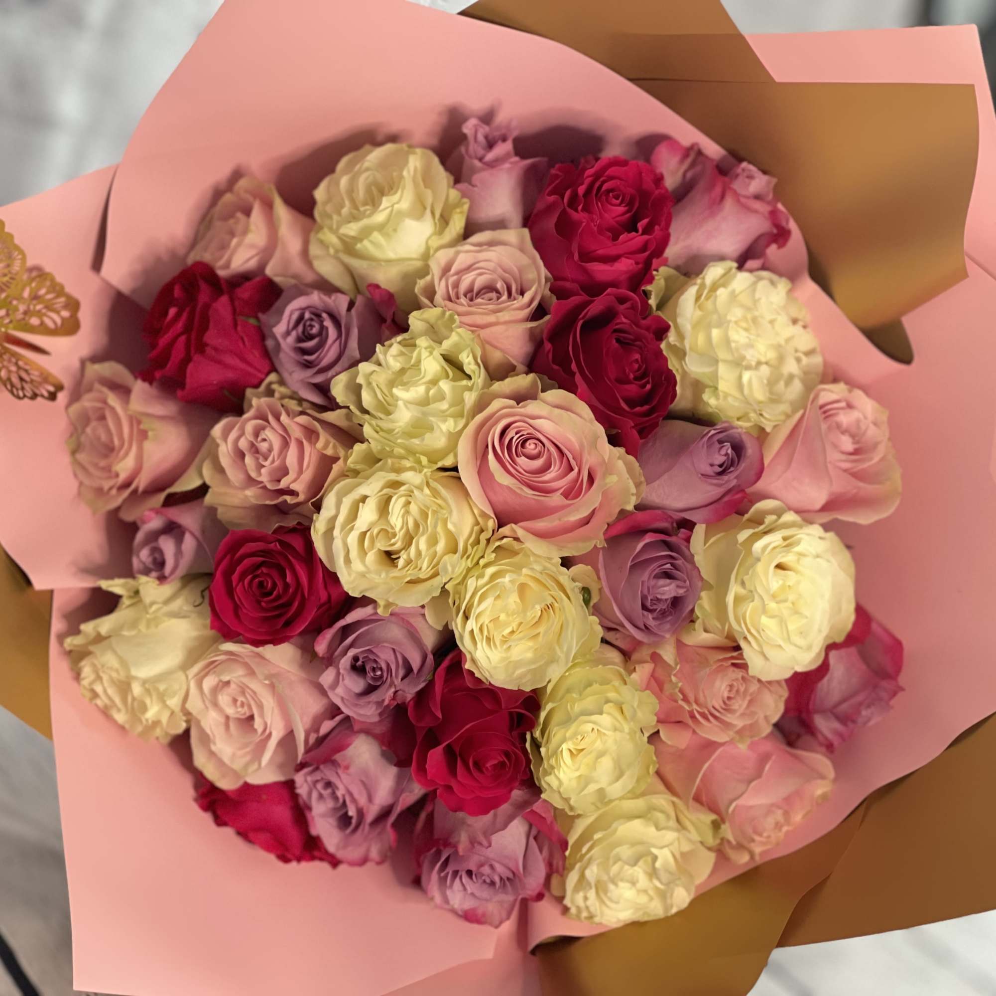 Bouquet of pink, red, and cream roses wrapped in pink paper