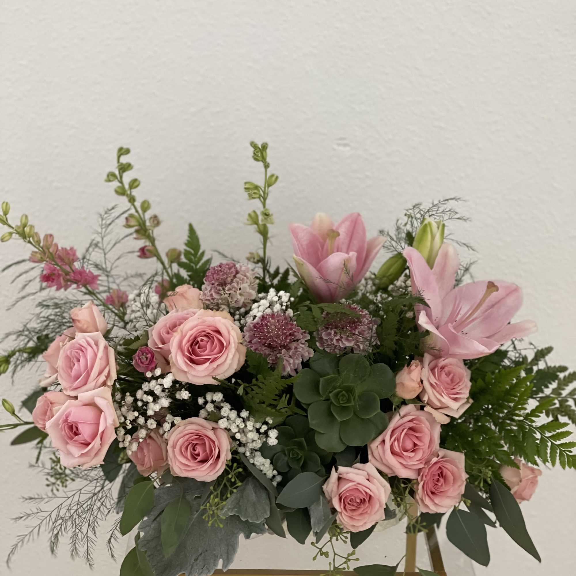 Pink roses and lilies arranged in a low bouquet with greenery