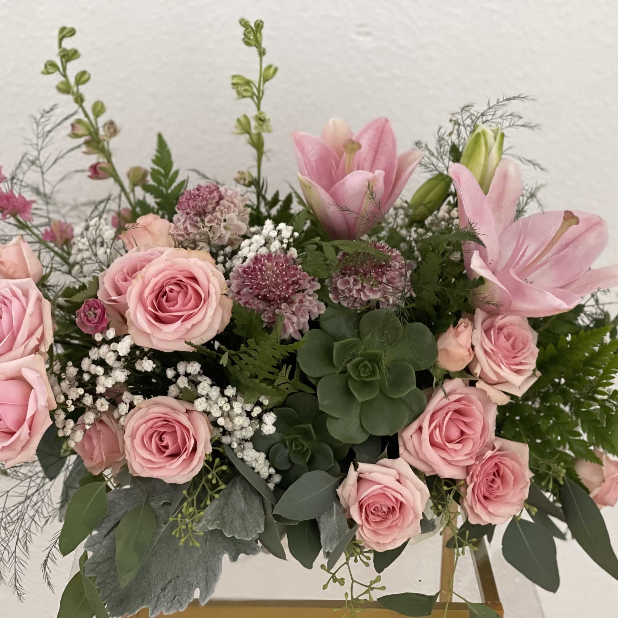 Pink roses and lilies arranged with greenery in a vase