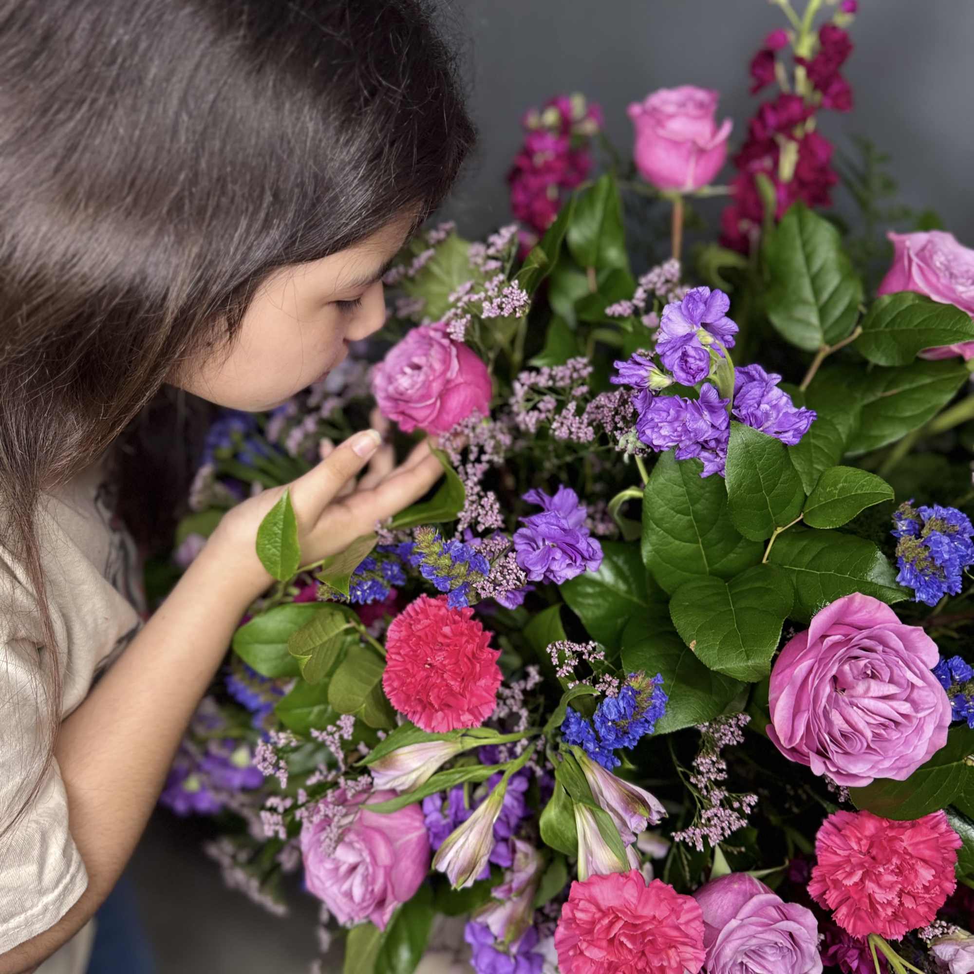 Girl smelling a bouquet of pink and purple flowers