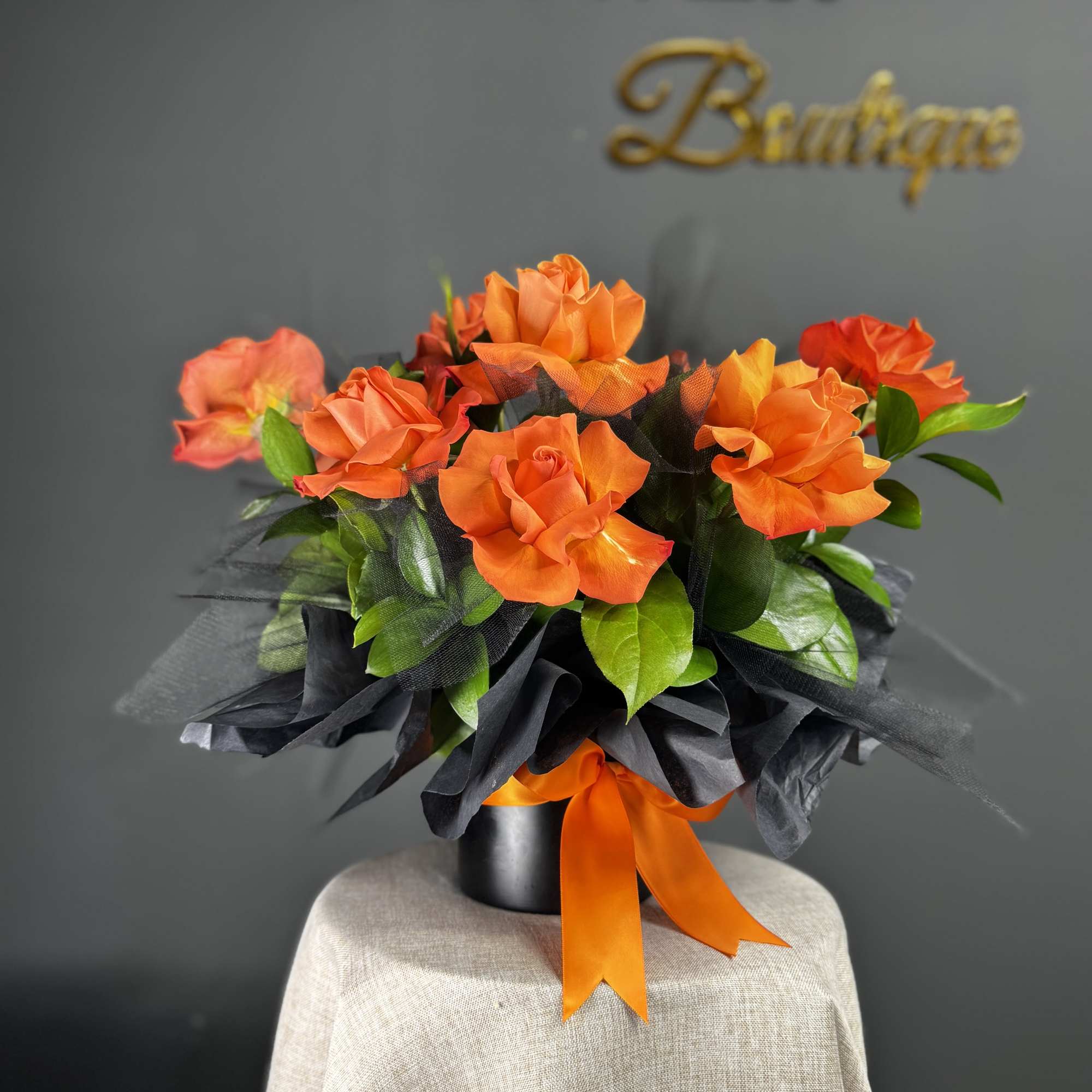 Orange roses in a black wrapped bouquet with an orange ribbon