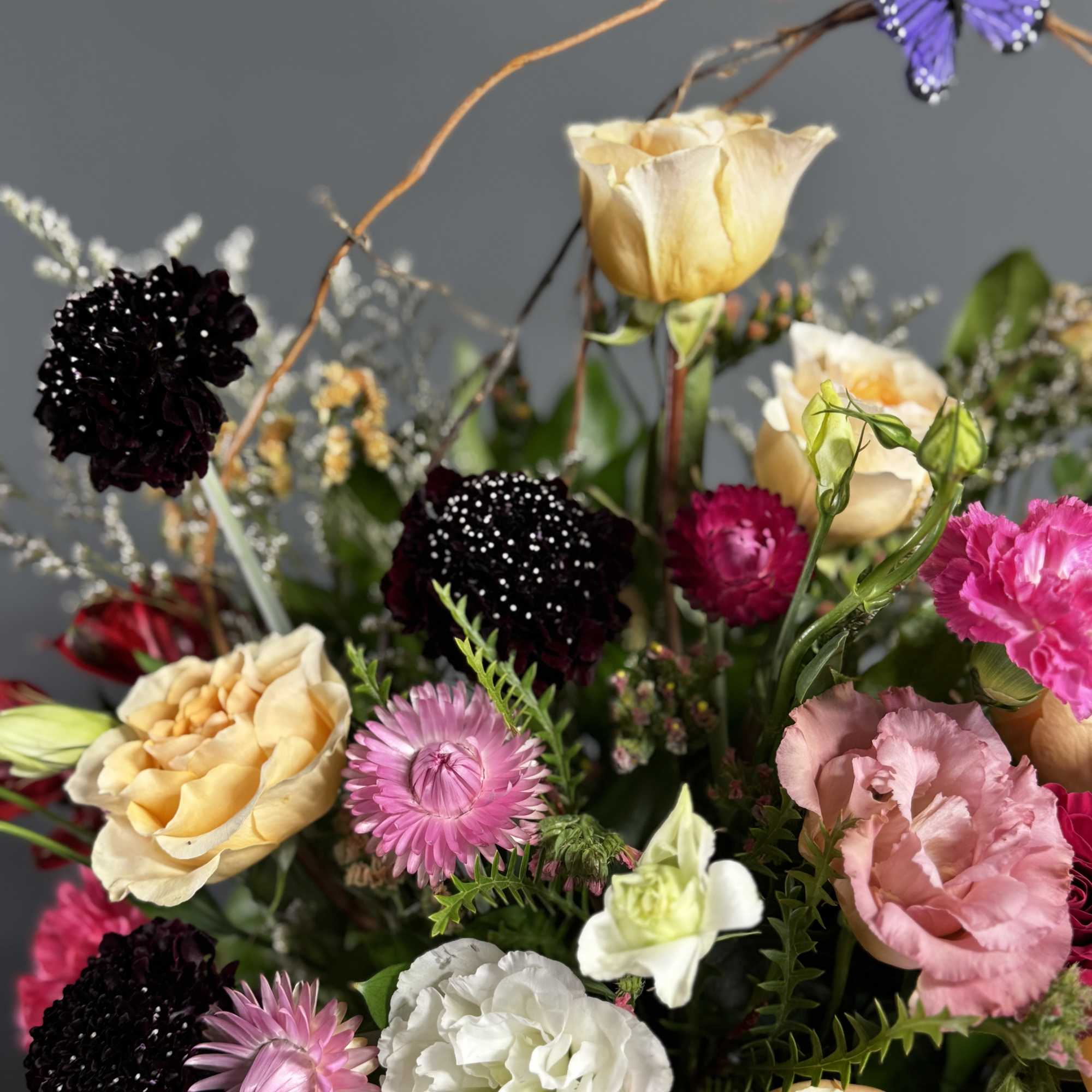 Mixed bouquet with roses, carnations, and daisies in cream, pink, and black