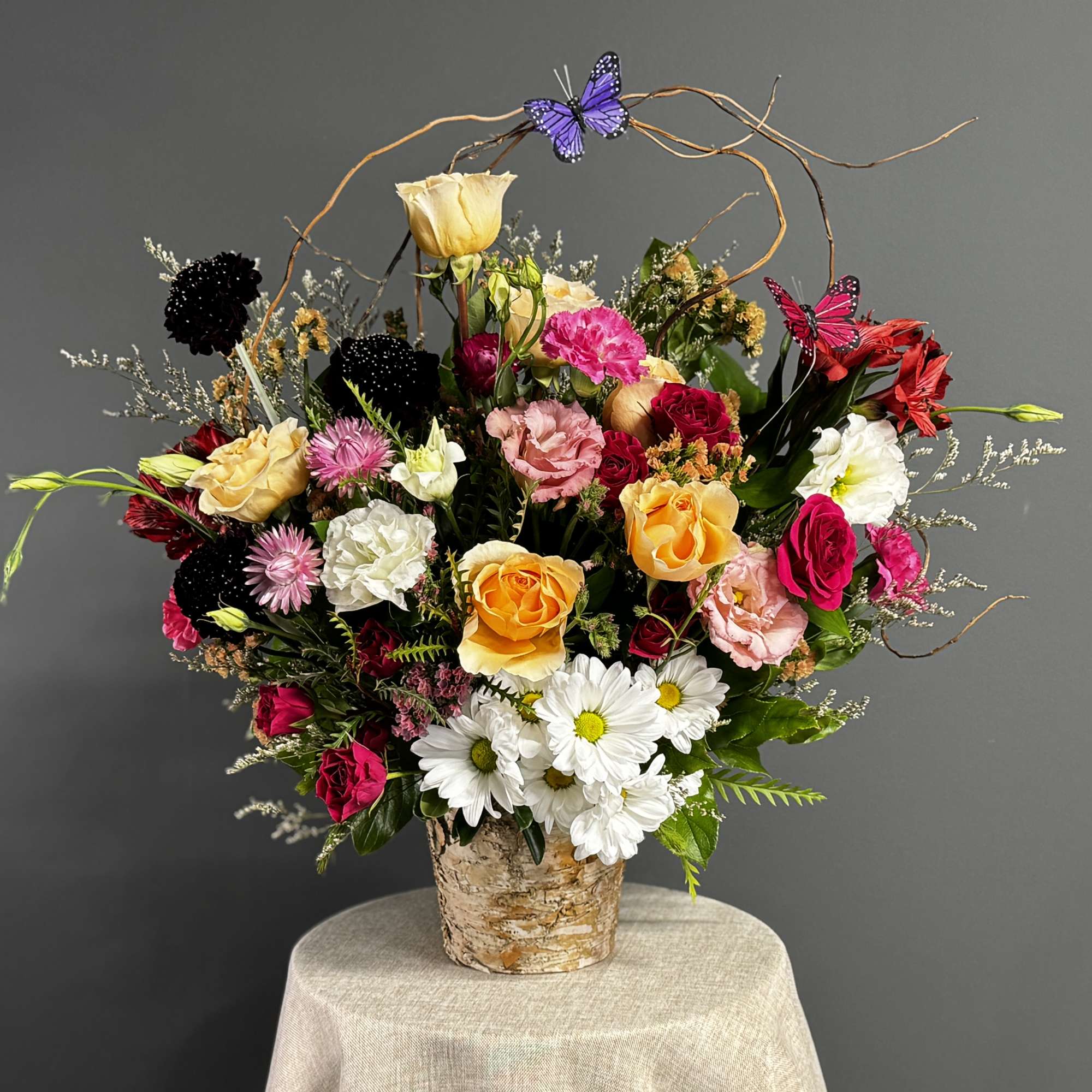 Mixed bouquet in a birch bark container with butterflies and curly branches