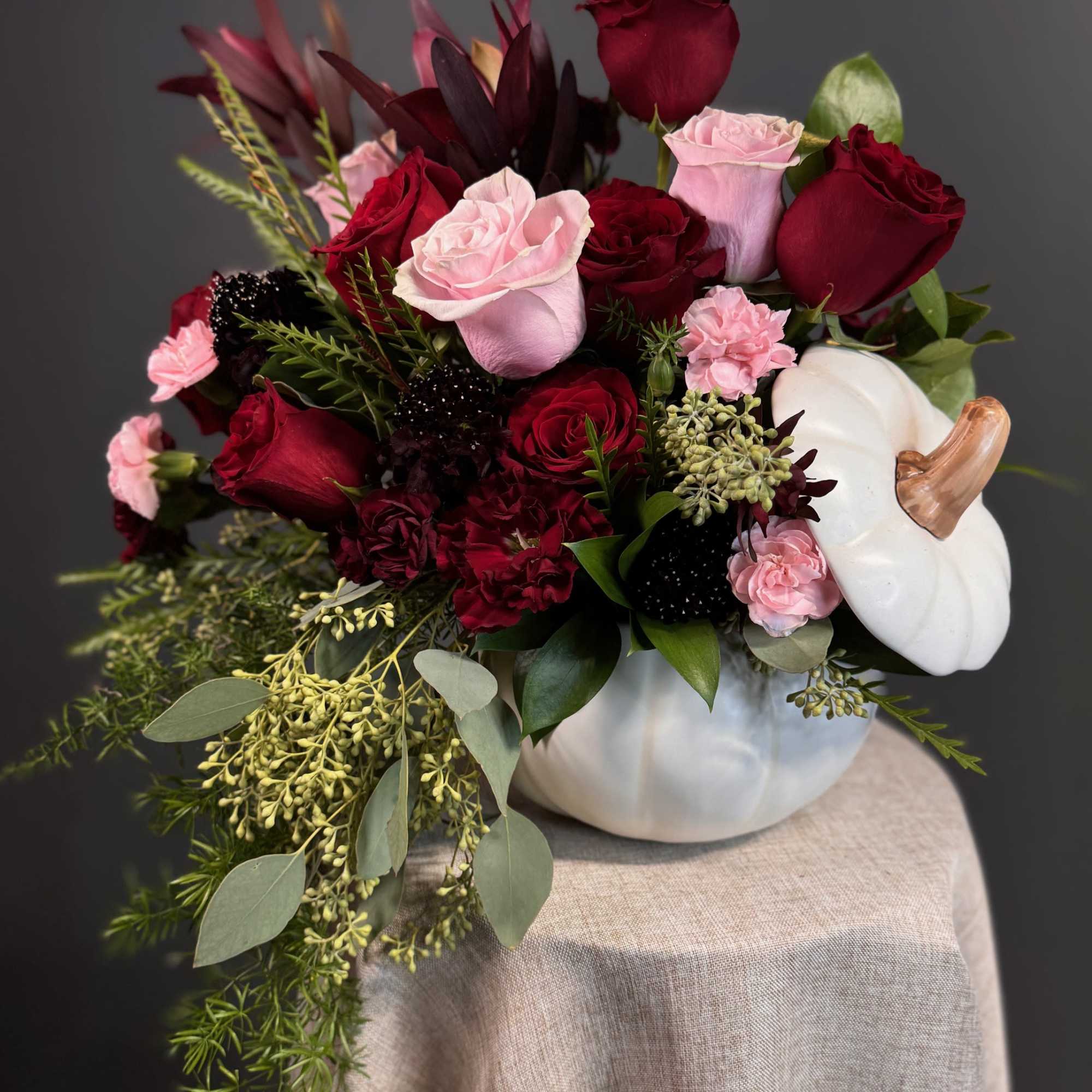A sophisticated mix of deep red and blush blooms, artfully arranged in, photo 3 of 4