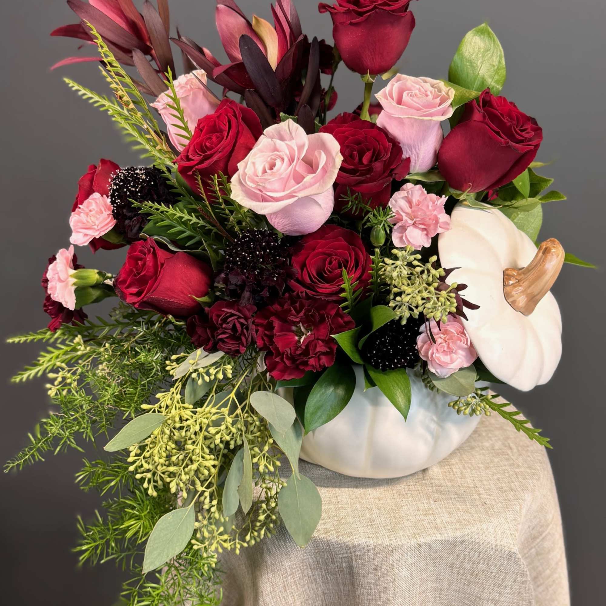 A sophisticated mix of deep red and blush blooms, artfully arranged in, photo 4 of 4