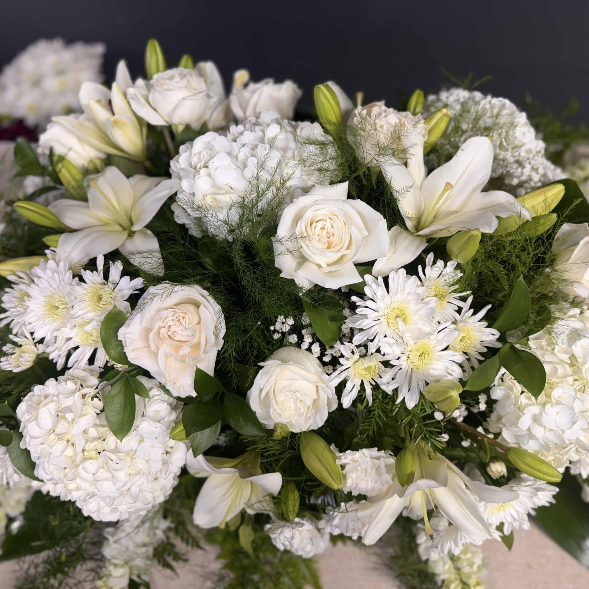 White floral arrangement with roses, lilies, and daisies