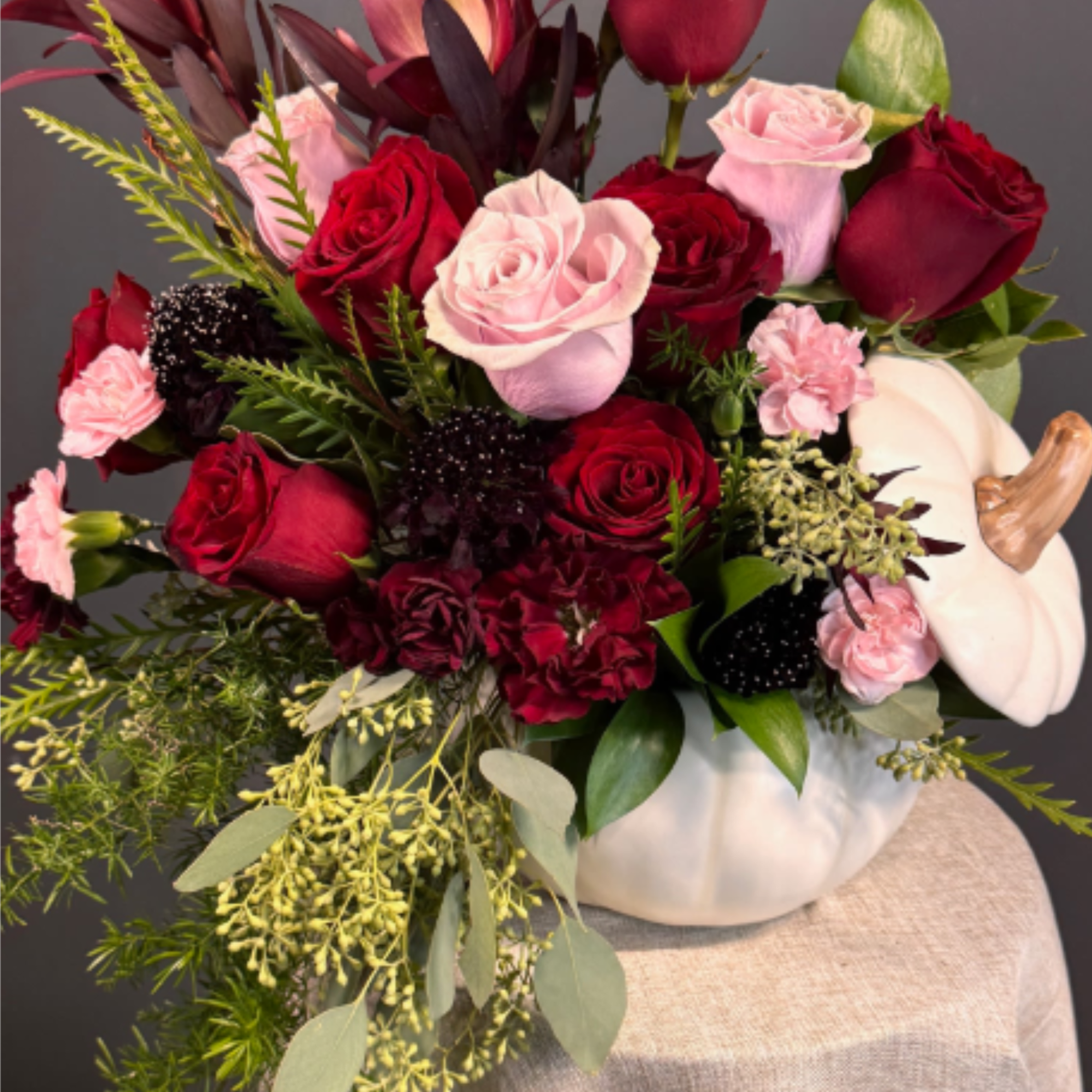 A sophisticated mix of deep red and blush blooms, artfully arranged in, photo 2 of 4