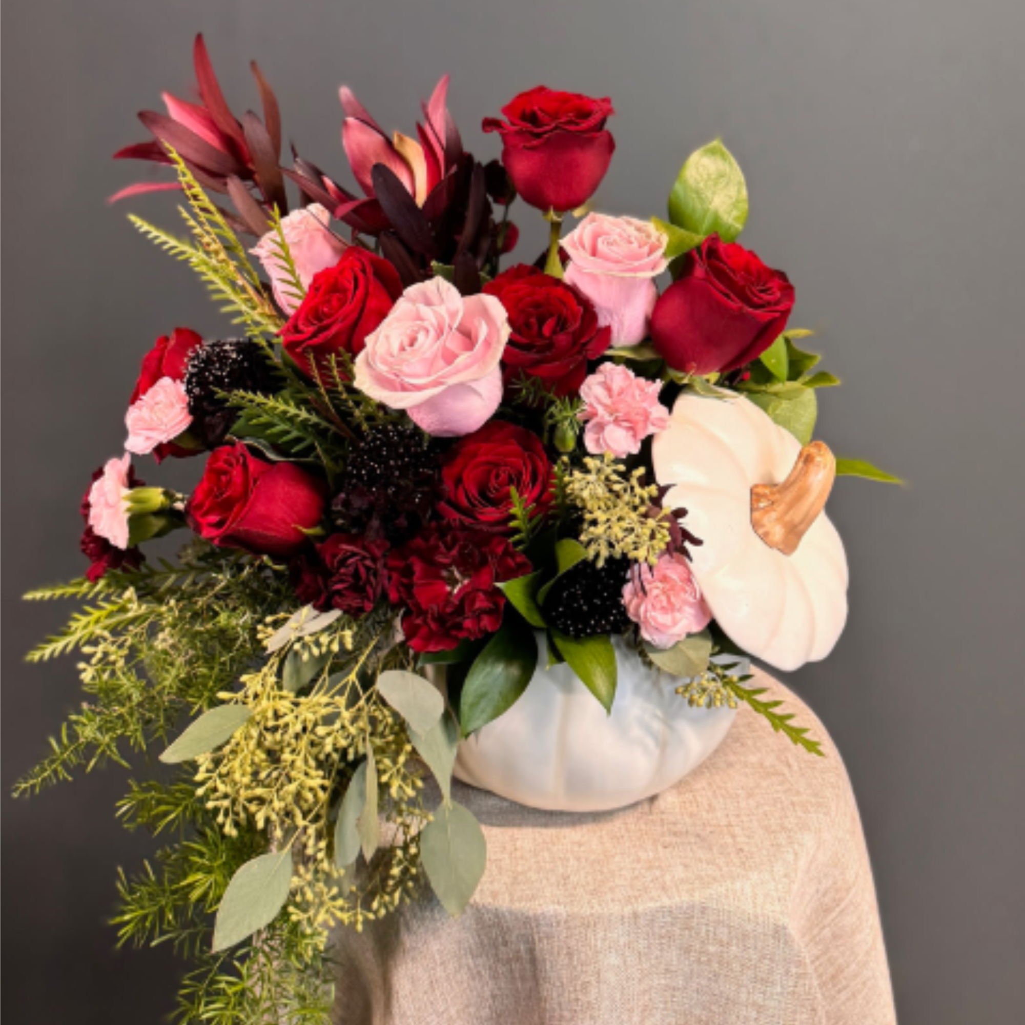 A sophisticated mix of deep red and blush blooms, artfully arranged in