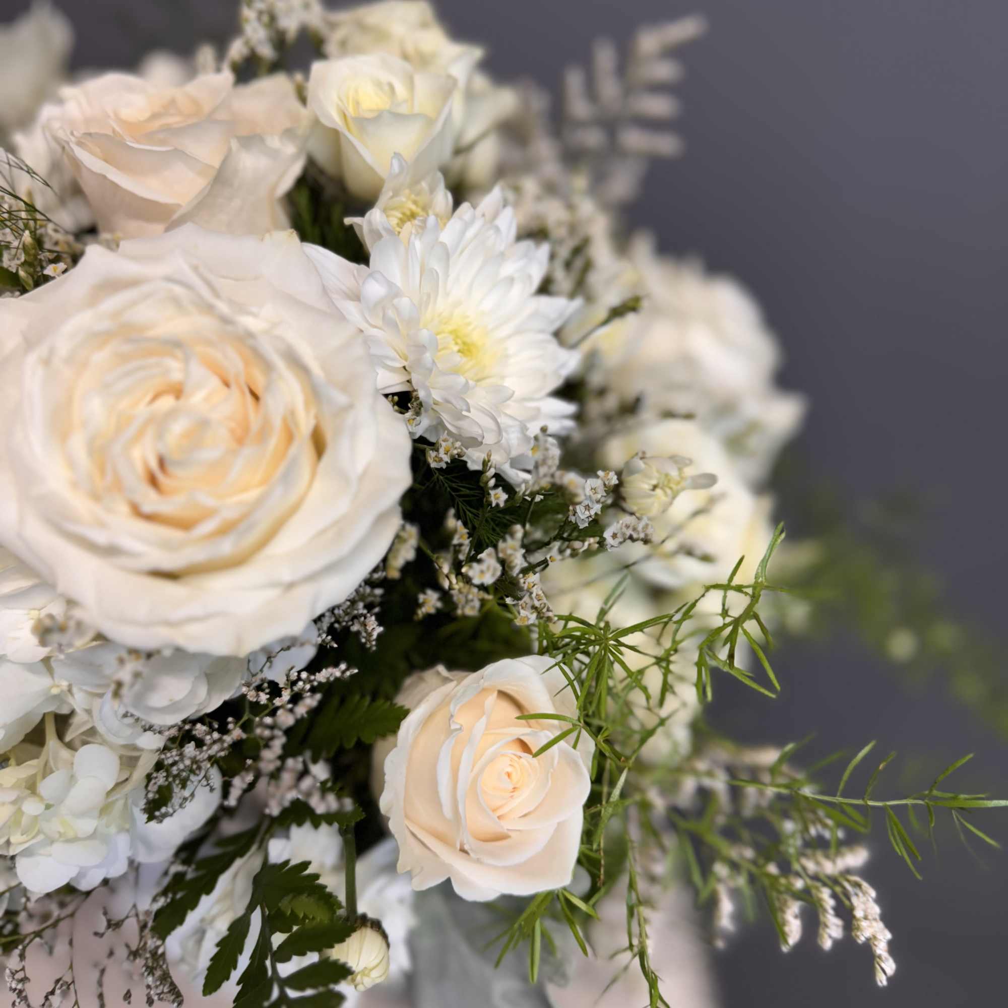Arrangement of ivory roses and white chrysanthemums in a soft neutral palette