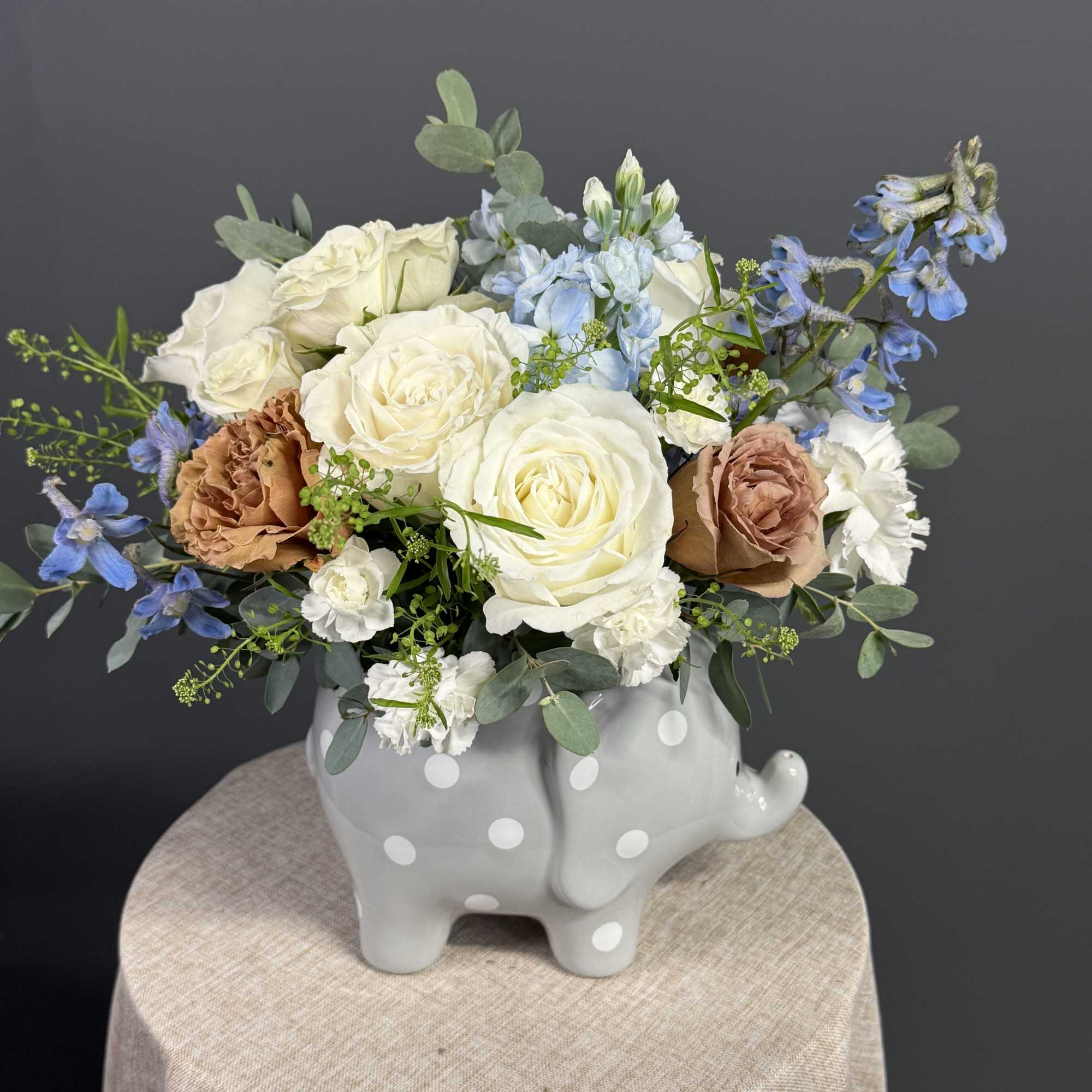 A charming baby boy arrangement featuring soft blue blooms, creamy white roses