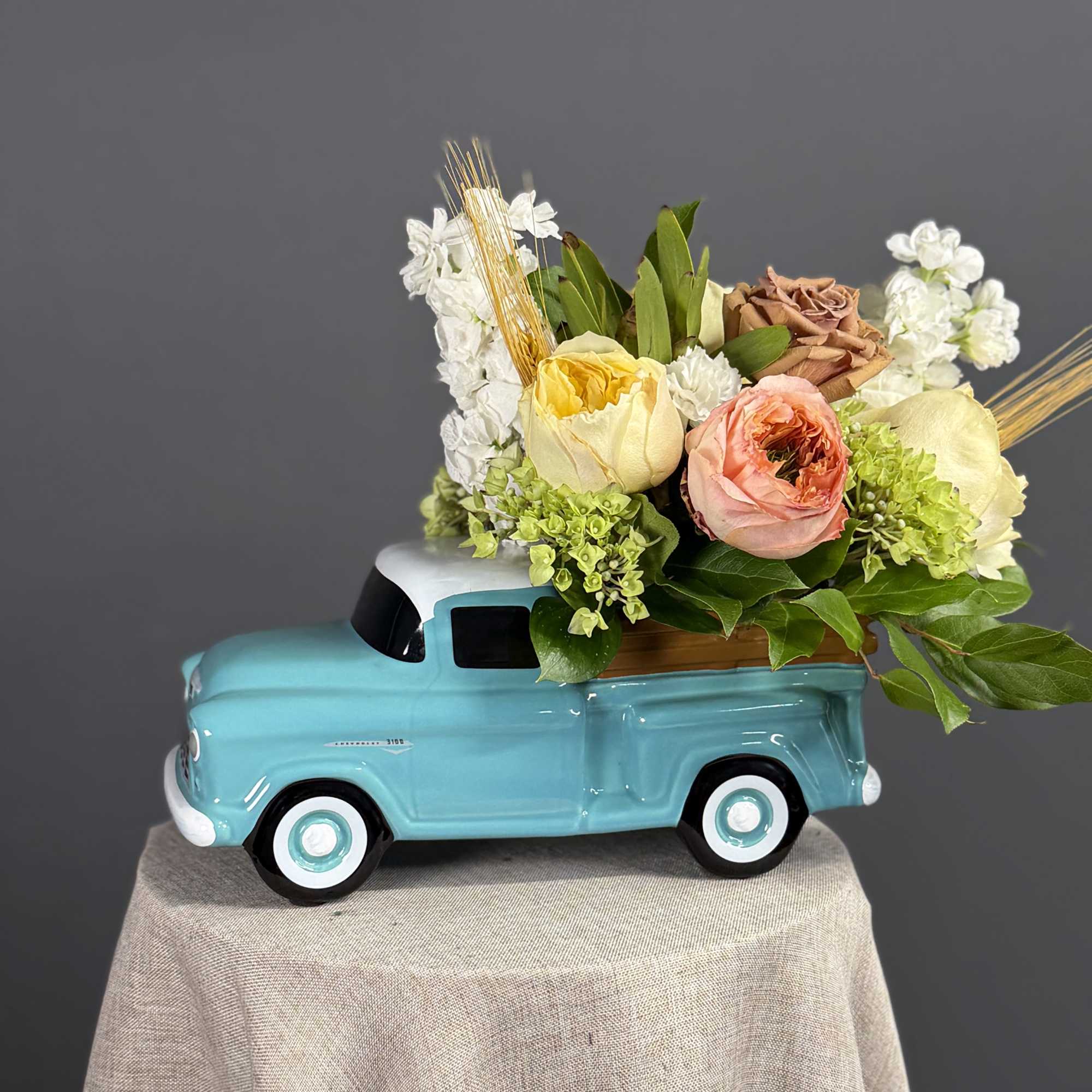 A glossy tale ceramic Ford pickup holds a cheerful, tightly packed cluster
