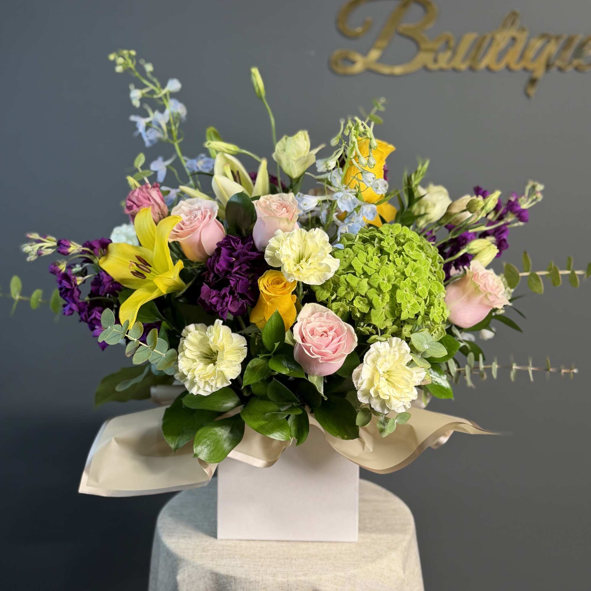 Colorful mixed flower arrangement with roses, lilies, and hydrangea in a white box container