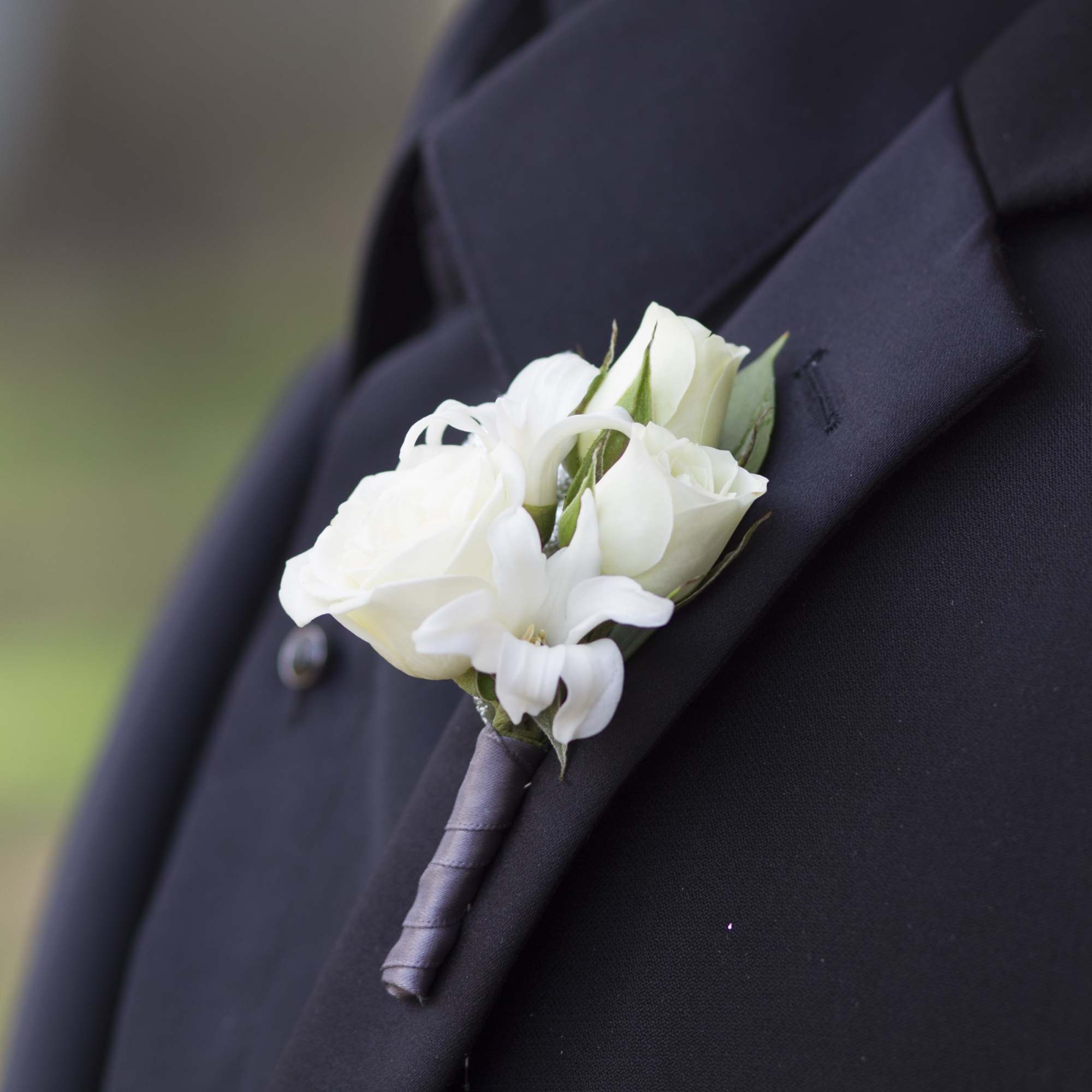 White rose boutonniere pinned to a black suit lapel