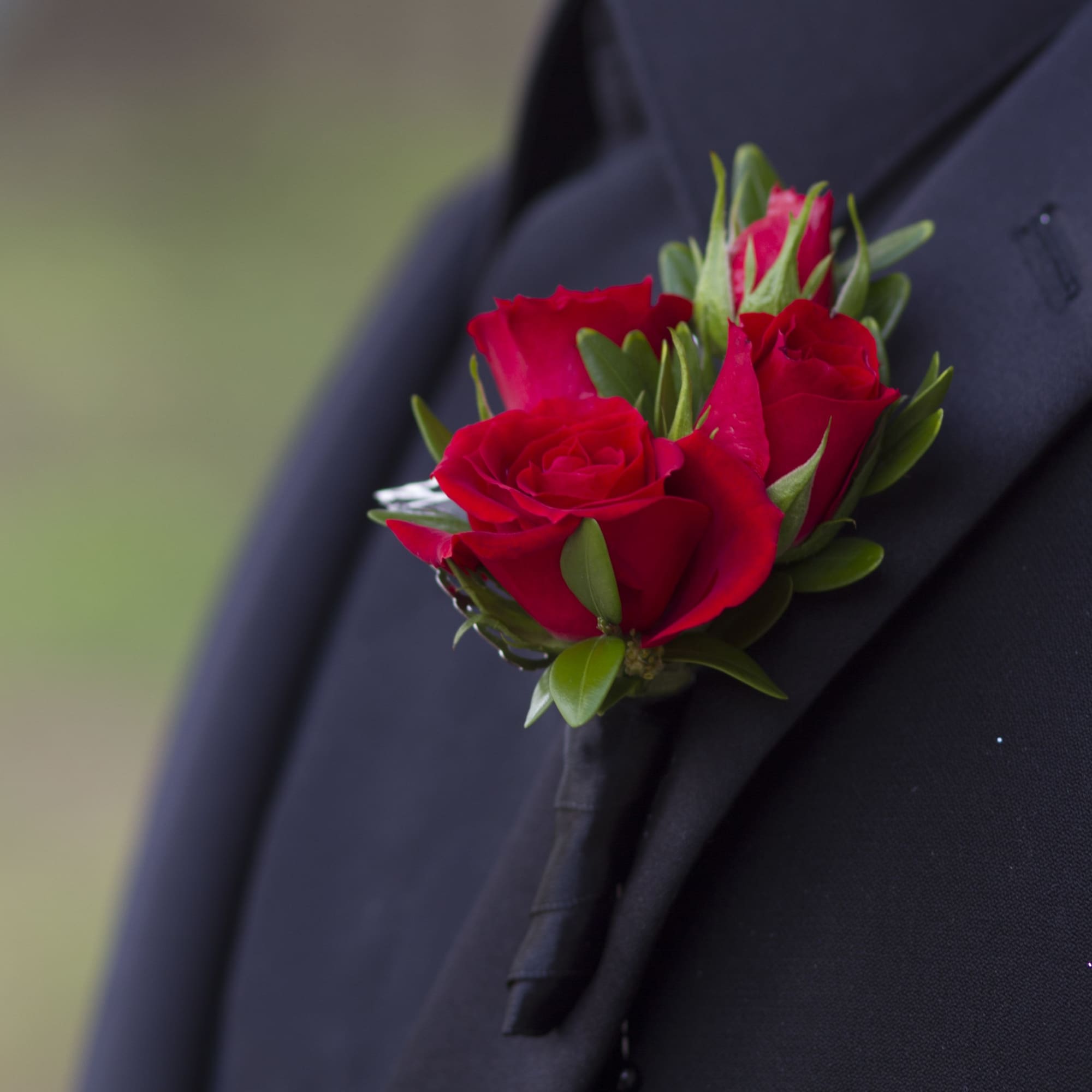 Red rose boutonniere pinned to a dark suit lapel